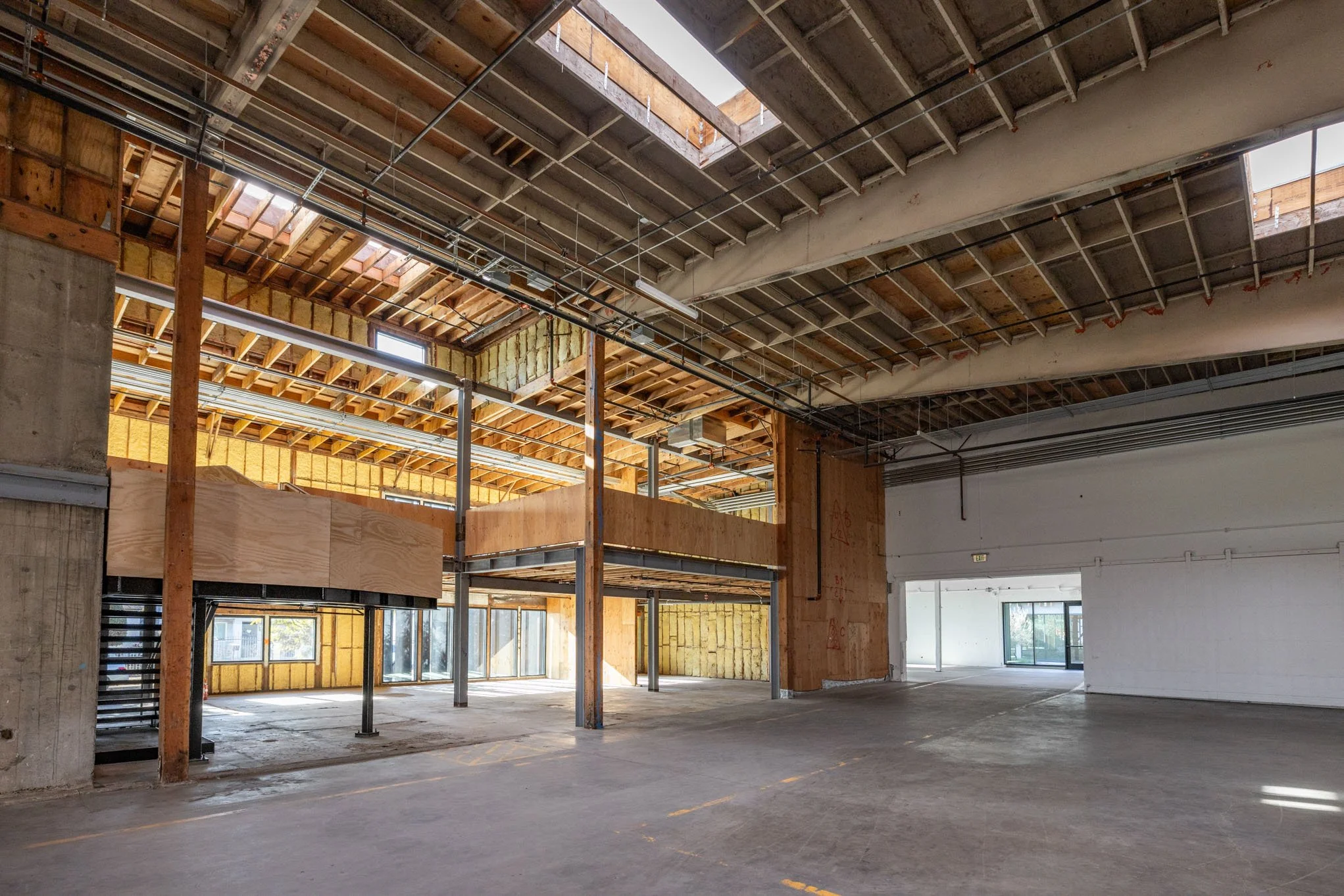 Interior of a building under construction with exposed wood framing, metal support beams, and unfinished walls and ceiling.