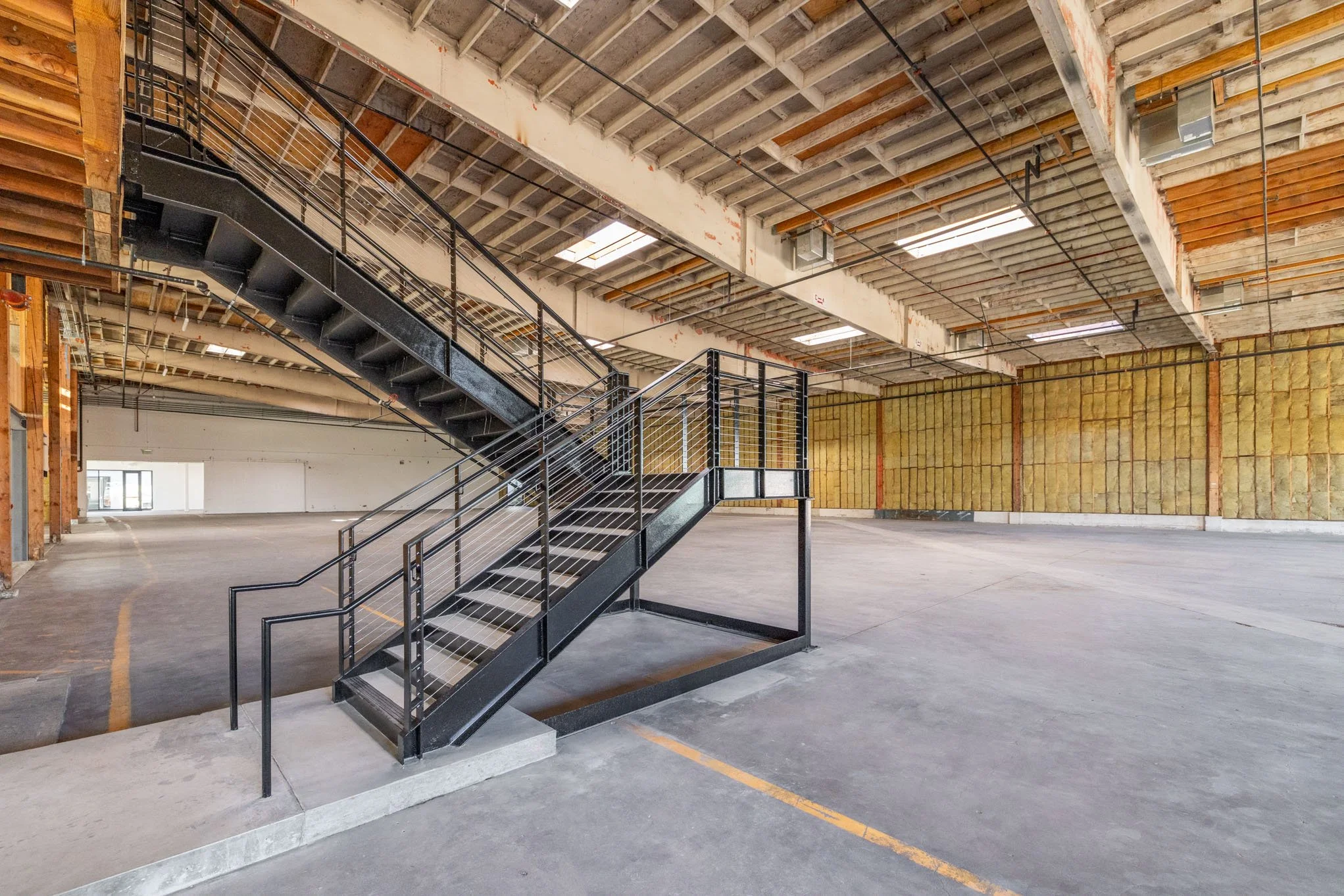 Empty indoor parking garage with a black metal staircase leading to an upper level.