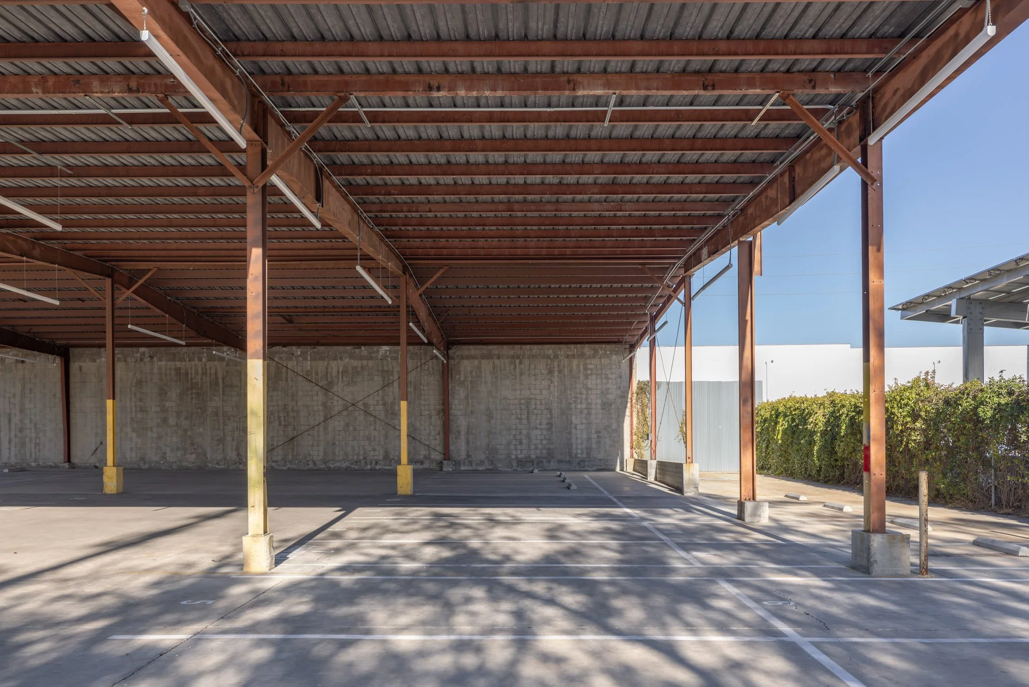 Empty outdoor warehouse parking lot with exposed metal roof and concrete wall.
