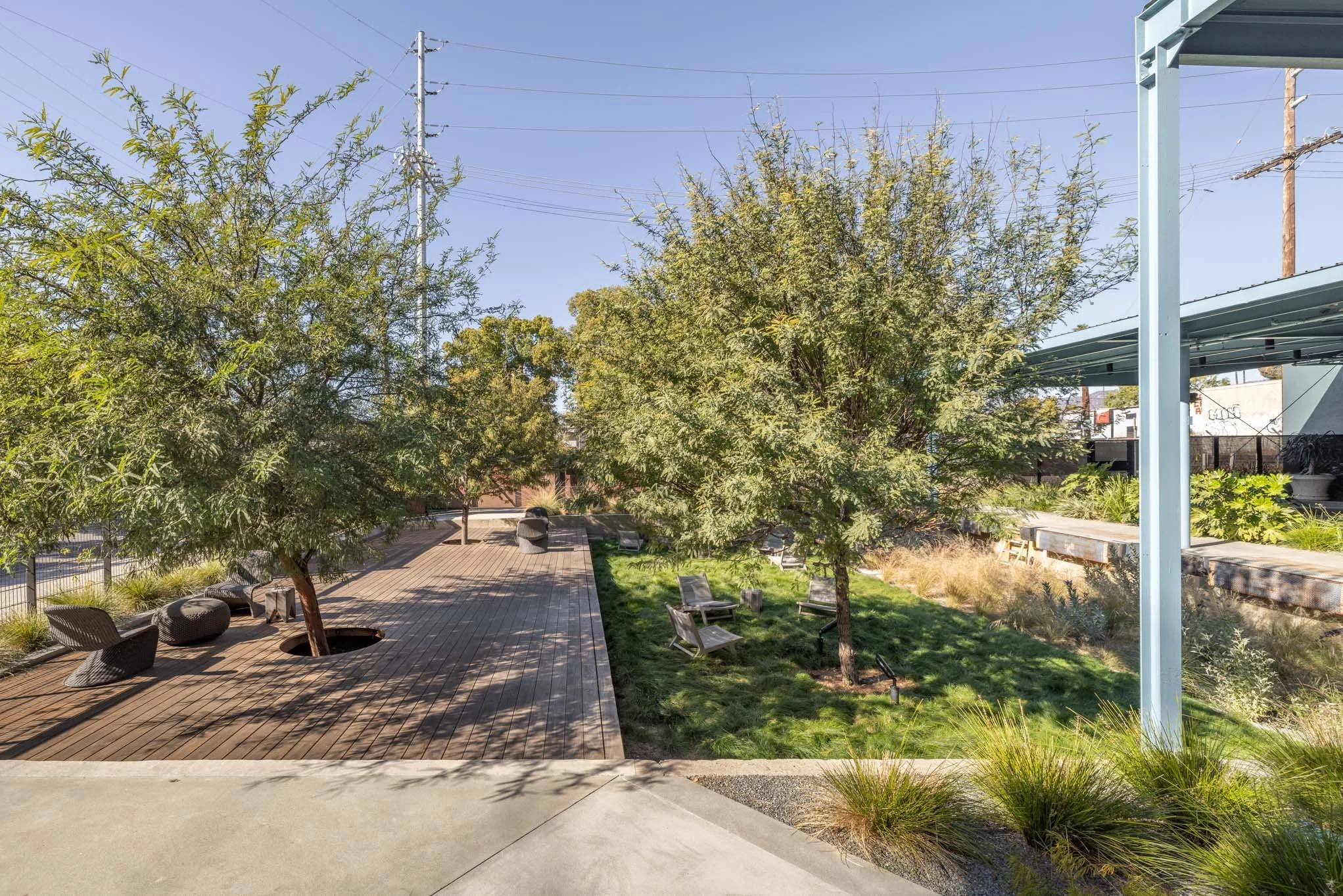 Outdoor park area with trees, wooden walkway, and seating.