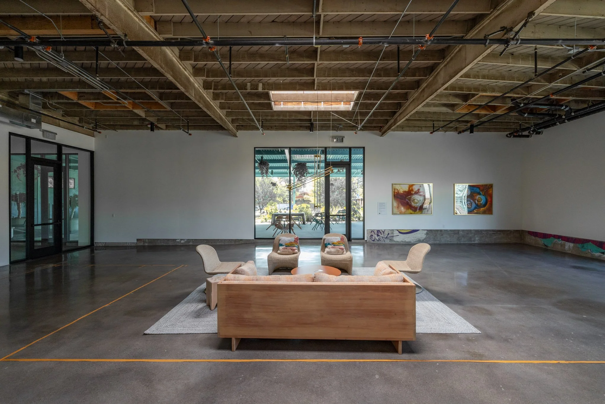 Empty art gallery with modern furniture and abstract paintings on the wall.