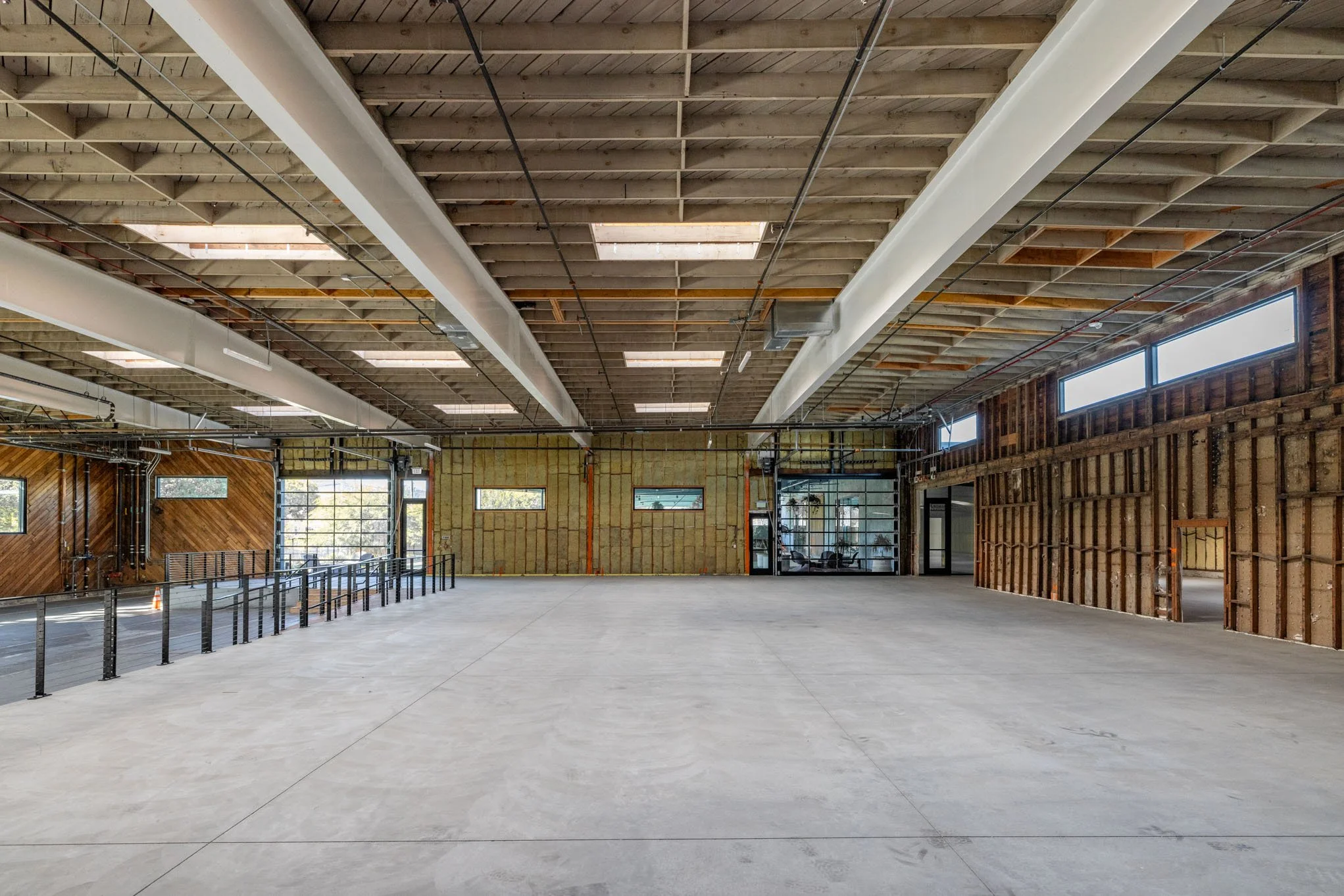 Empty interior space under construction with exposed wooden ceiling, walls, and a concrete floor.
