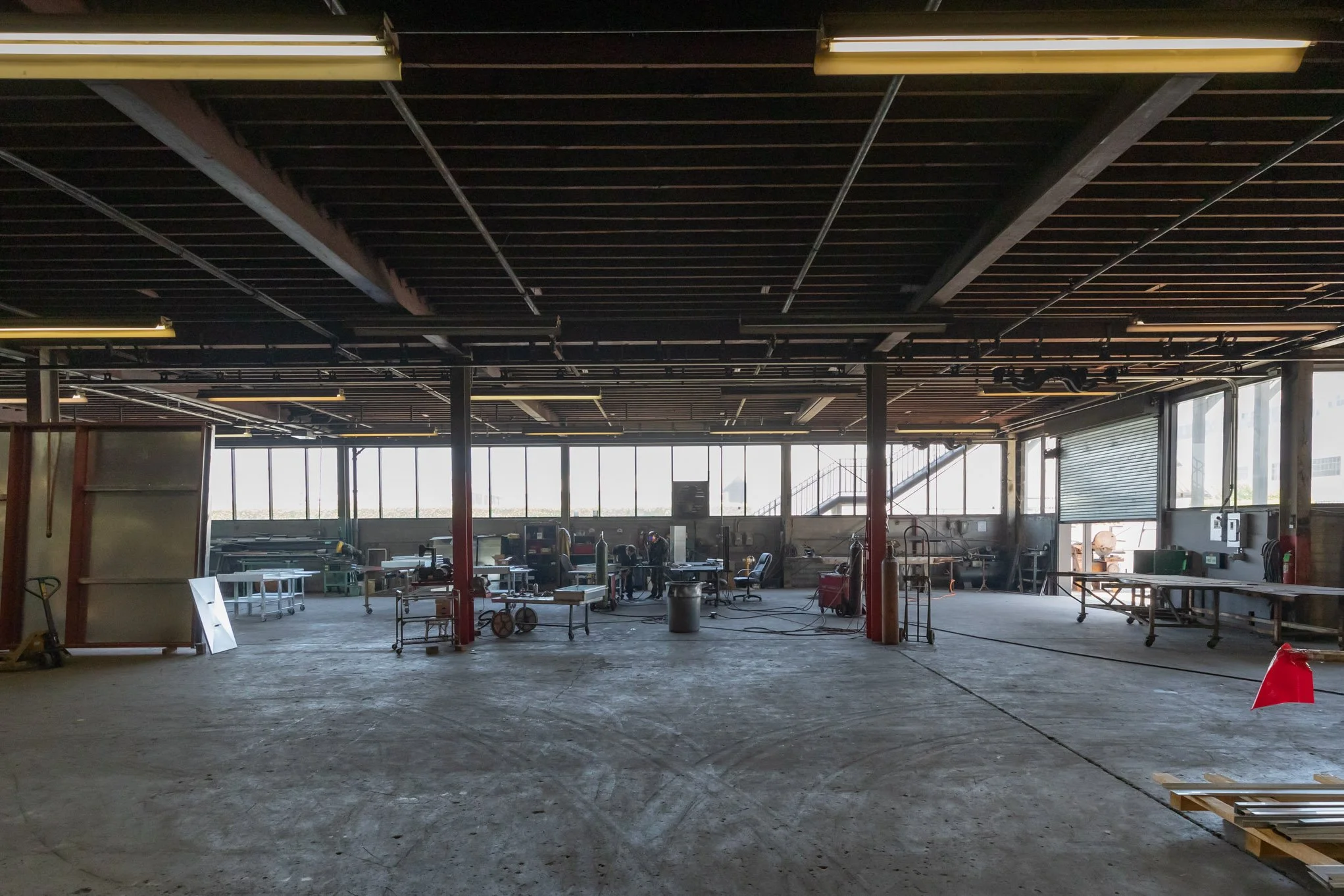 Underground construction site with concrete floor, work tables, tools, and large windows allowing natural light.