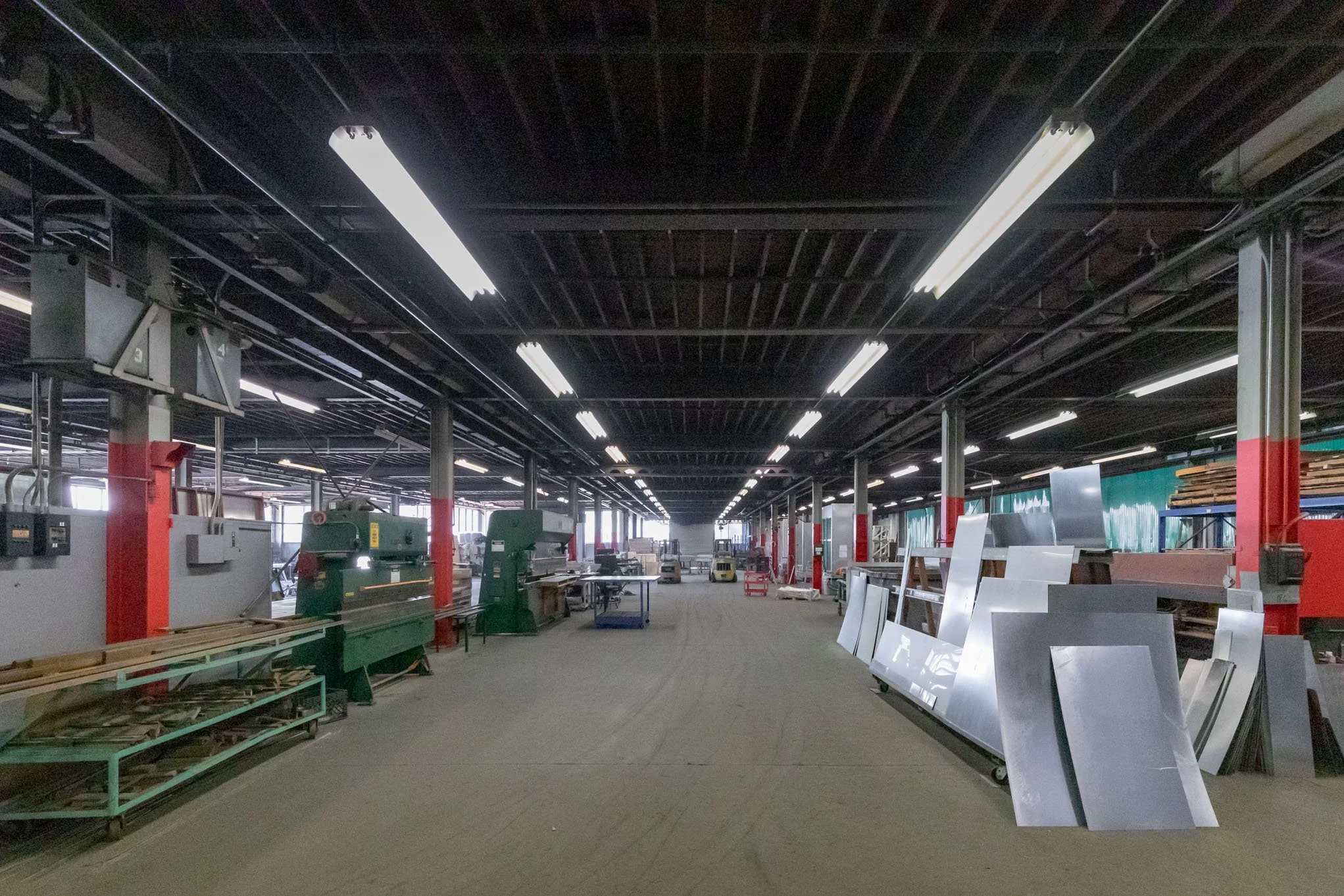 Industrial workshop with metal sheets and machinery inside a large warehouse