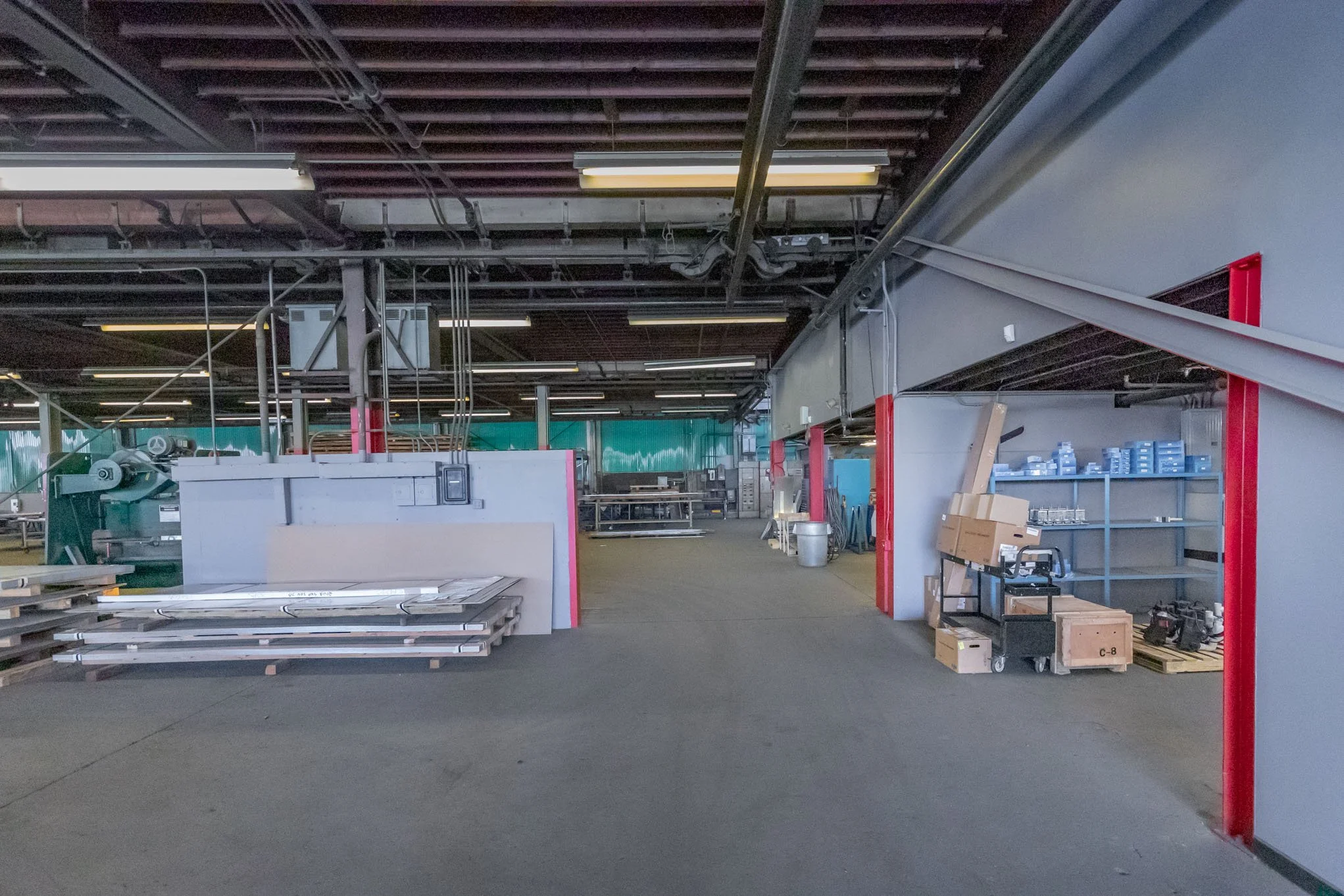 Empty industrial workspace with storage shelves, tools, and equipment.