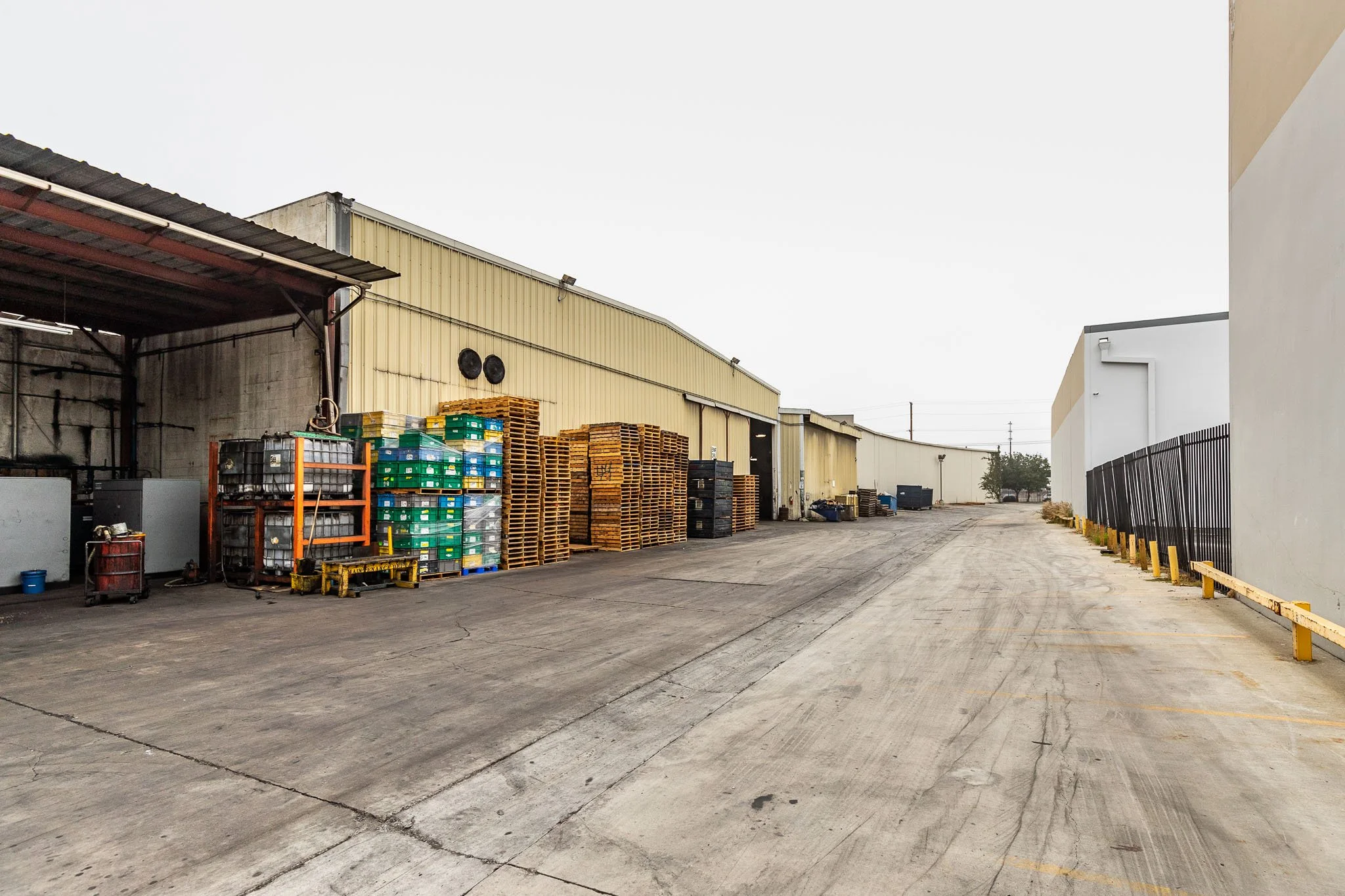 Empty industrial outdoor warehouse yard with stacked pallets and storage equipment