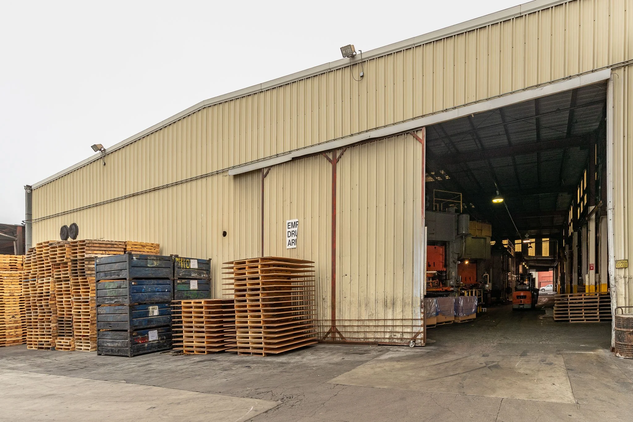 Industrial warehouse with pallets and metal storage containers outside and inside.