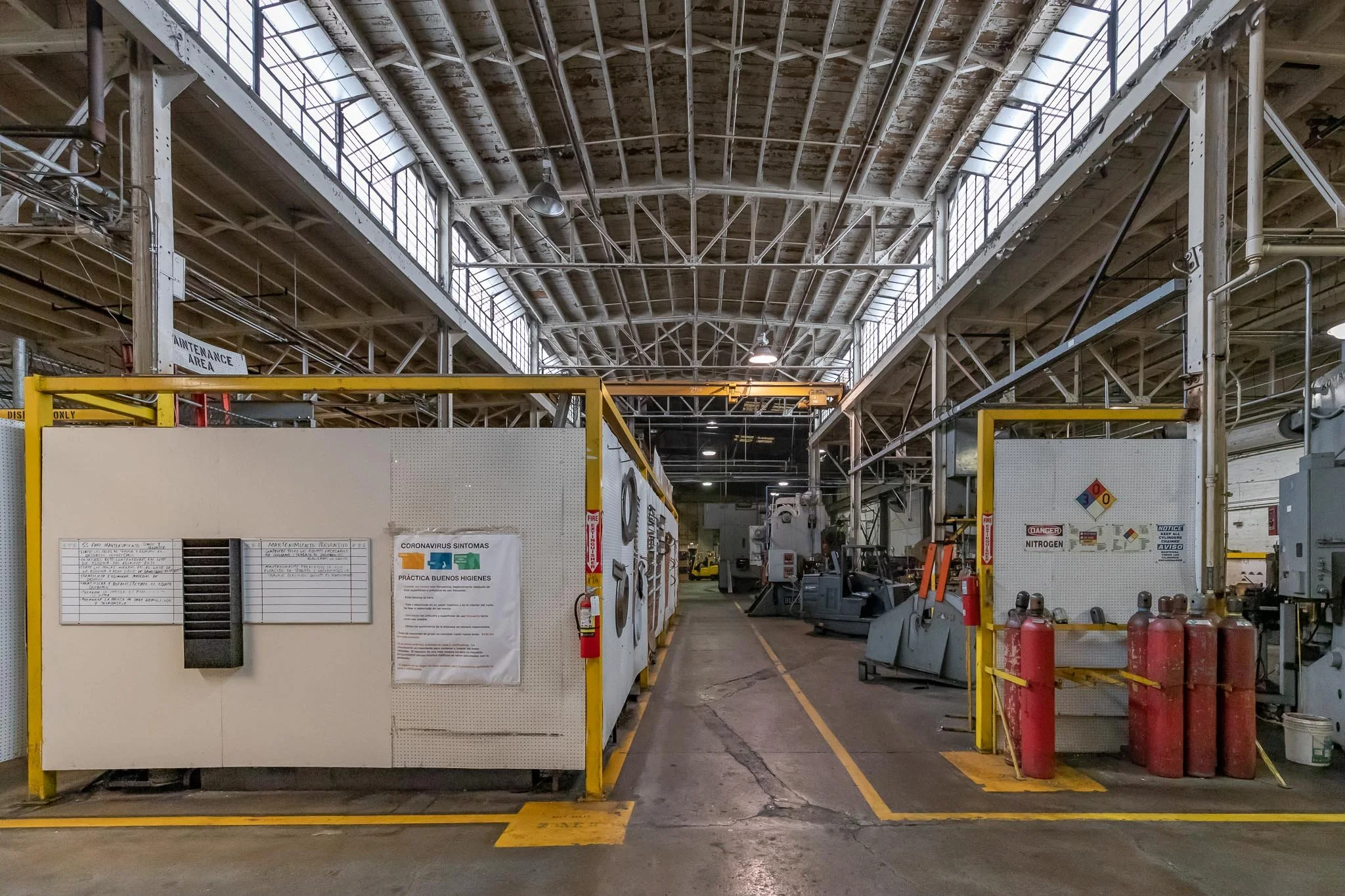 Industrial warehouse with equipment, safety signs, and fire extinguishers.