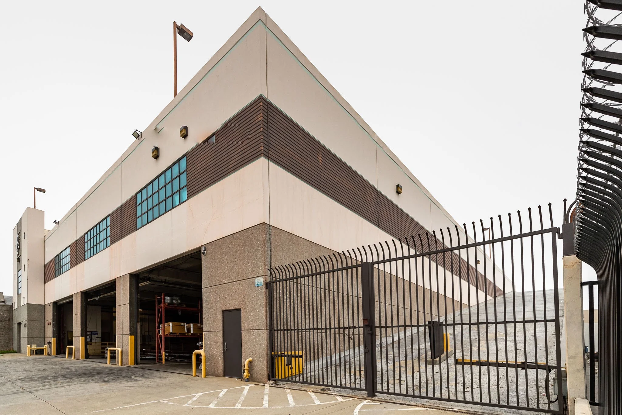 Exterior of a modern warehouse with a gated entrance and loading dock area.
