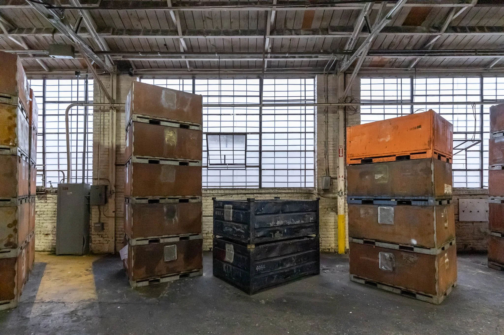 Industrial warehouse with stacked metal crates and large windows in the background.