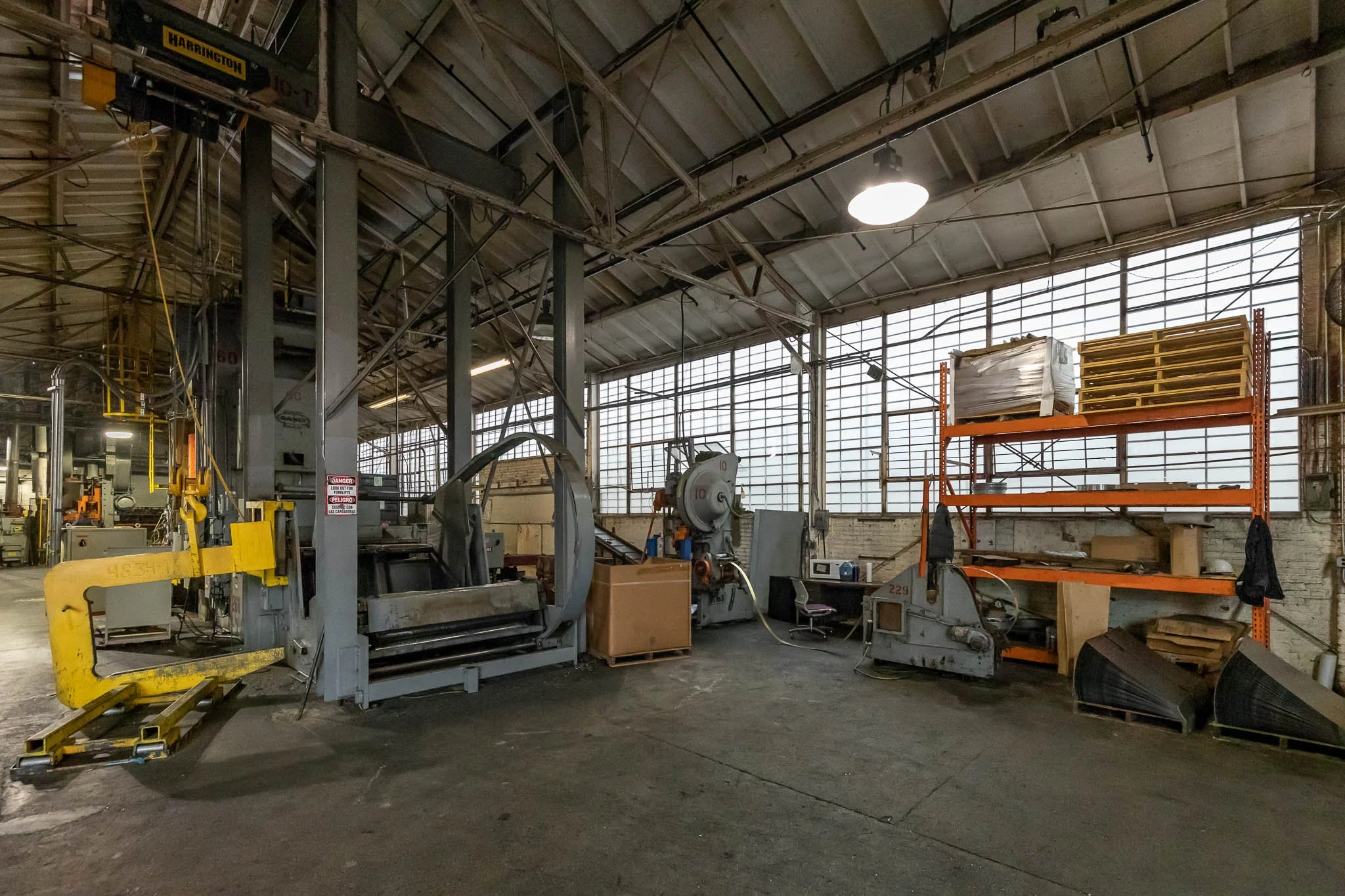 Industrial factory with metal machinery, orange shelving, and large windows in the background.