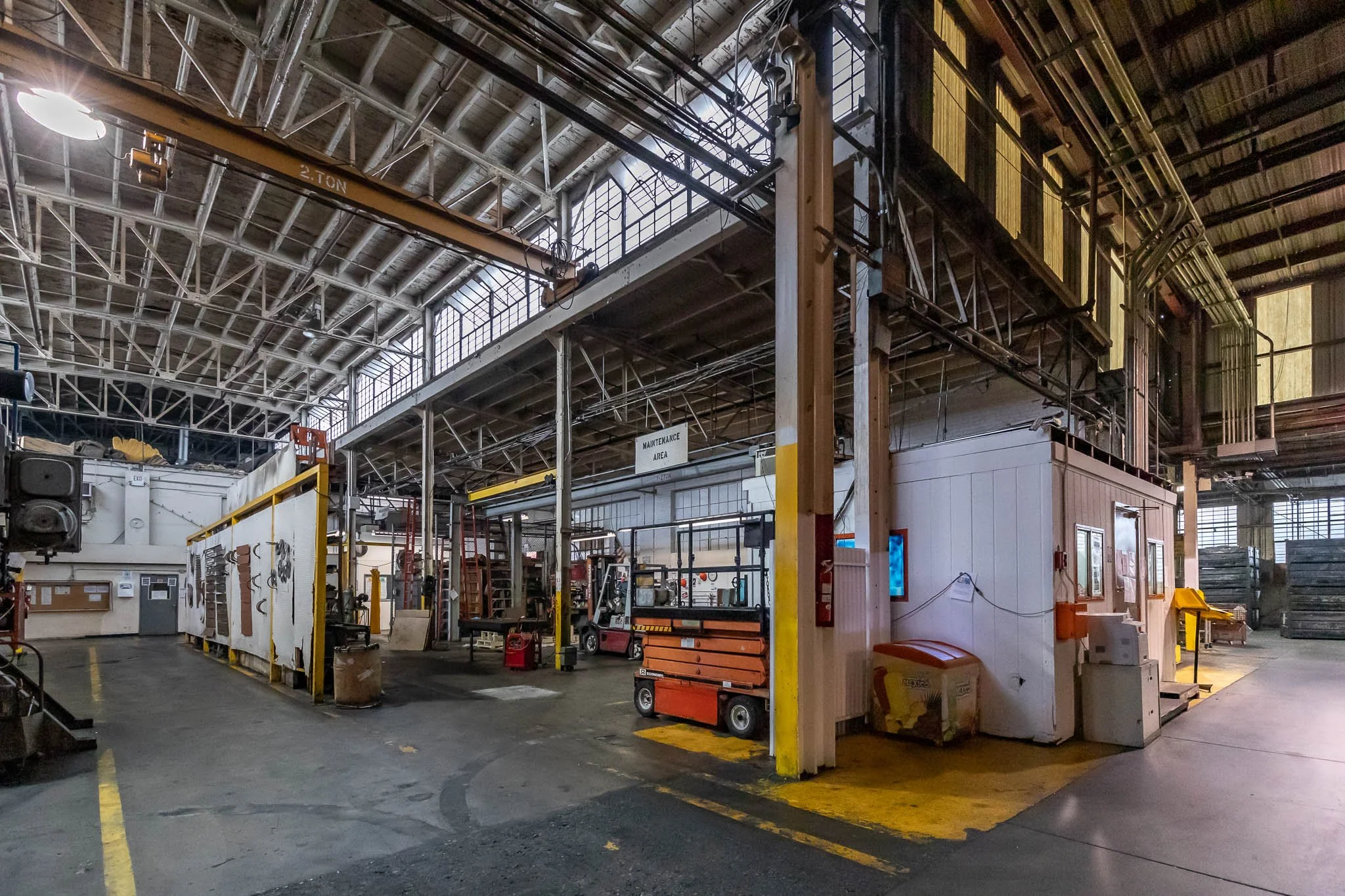 Interior view of an industrial warehouse or factory with equipment, carts, and a maintenance area.