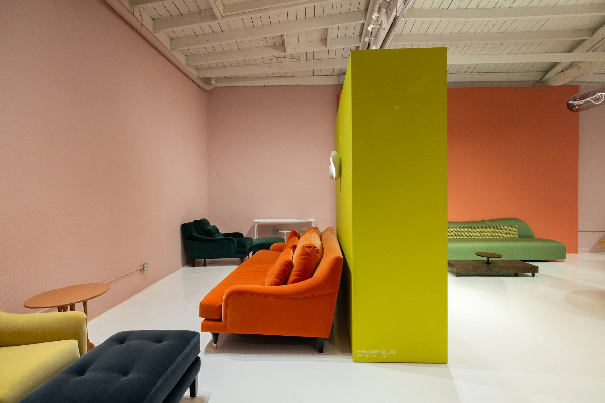 Colorful modern lounge with pink, orange, green, and yellow chairs and sofas in an art gallery setting