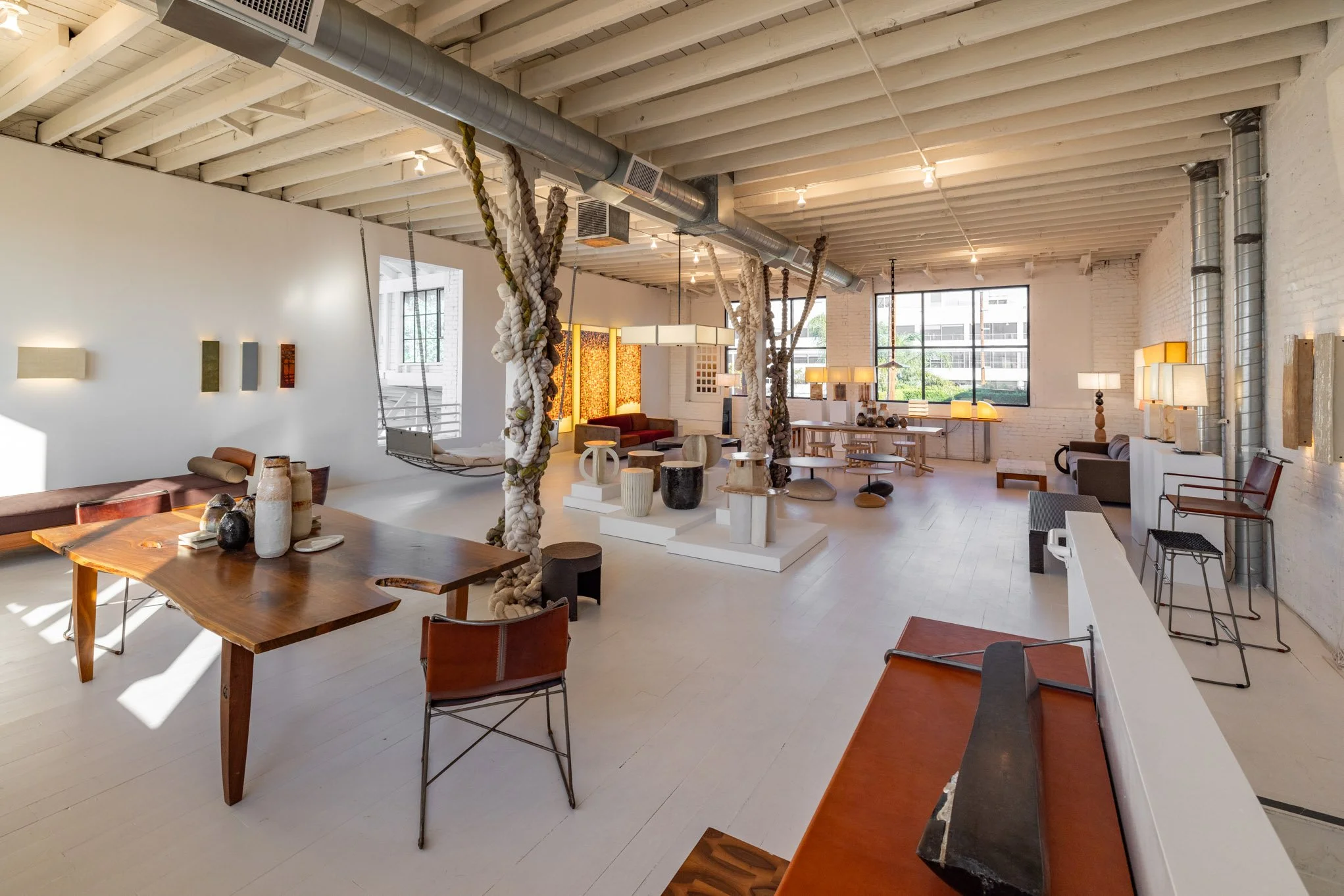 Interior of a modern art gallery with sculptures, seating, and decorative lighting.