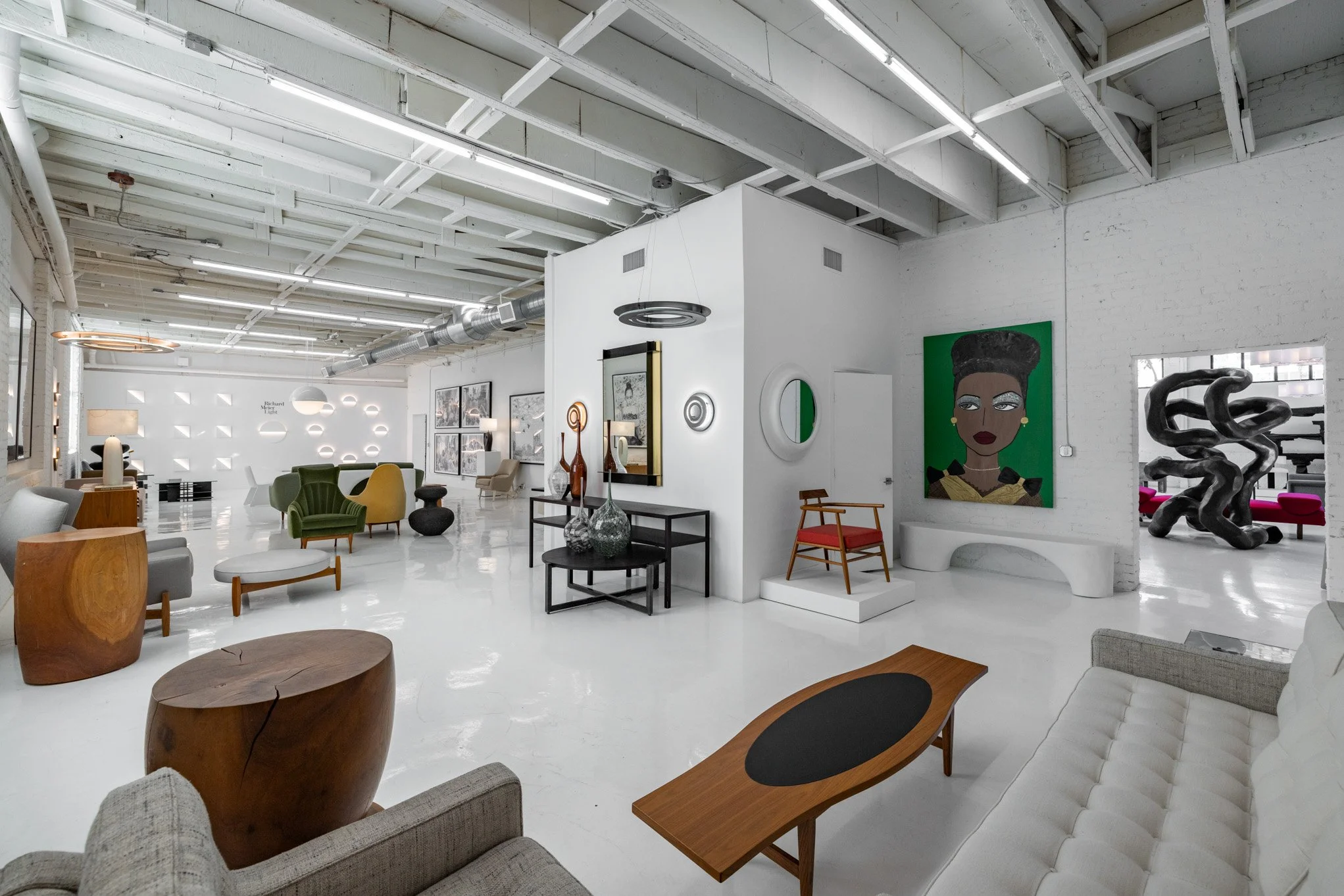 Art gallery with white walls, modern furniture, and colorful paintings and sculptures.