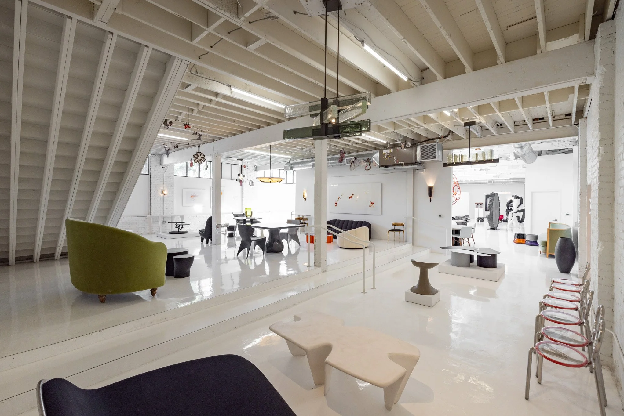 Interior of a modern, minimalist art gallery with white walls, various contemporary sculptures, and seating areas.