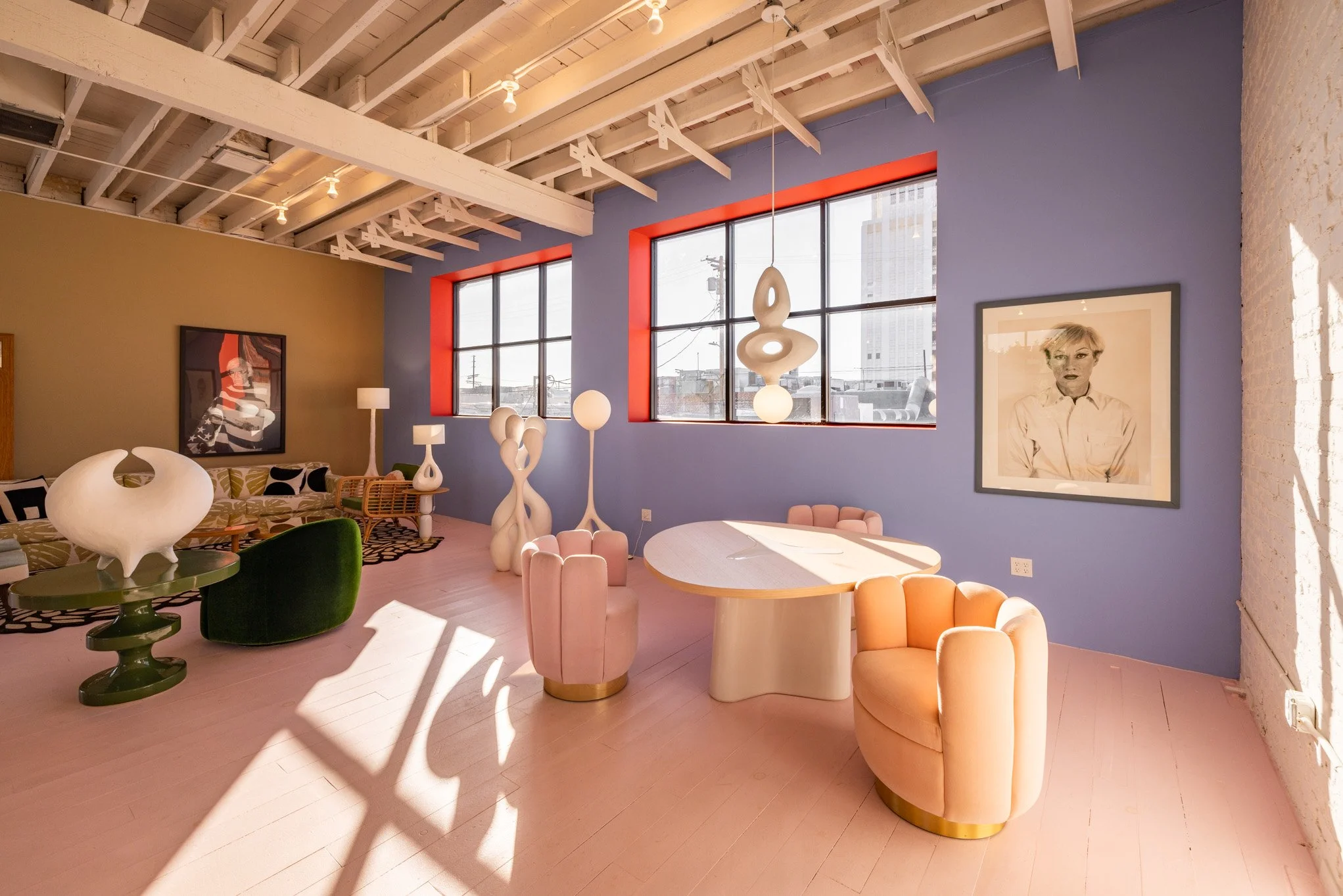 Bright, colorful interior space with modern furniture, art, and large windows letting in natural light.