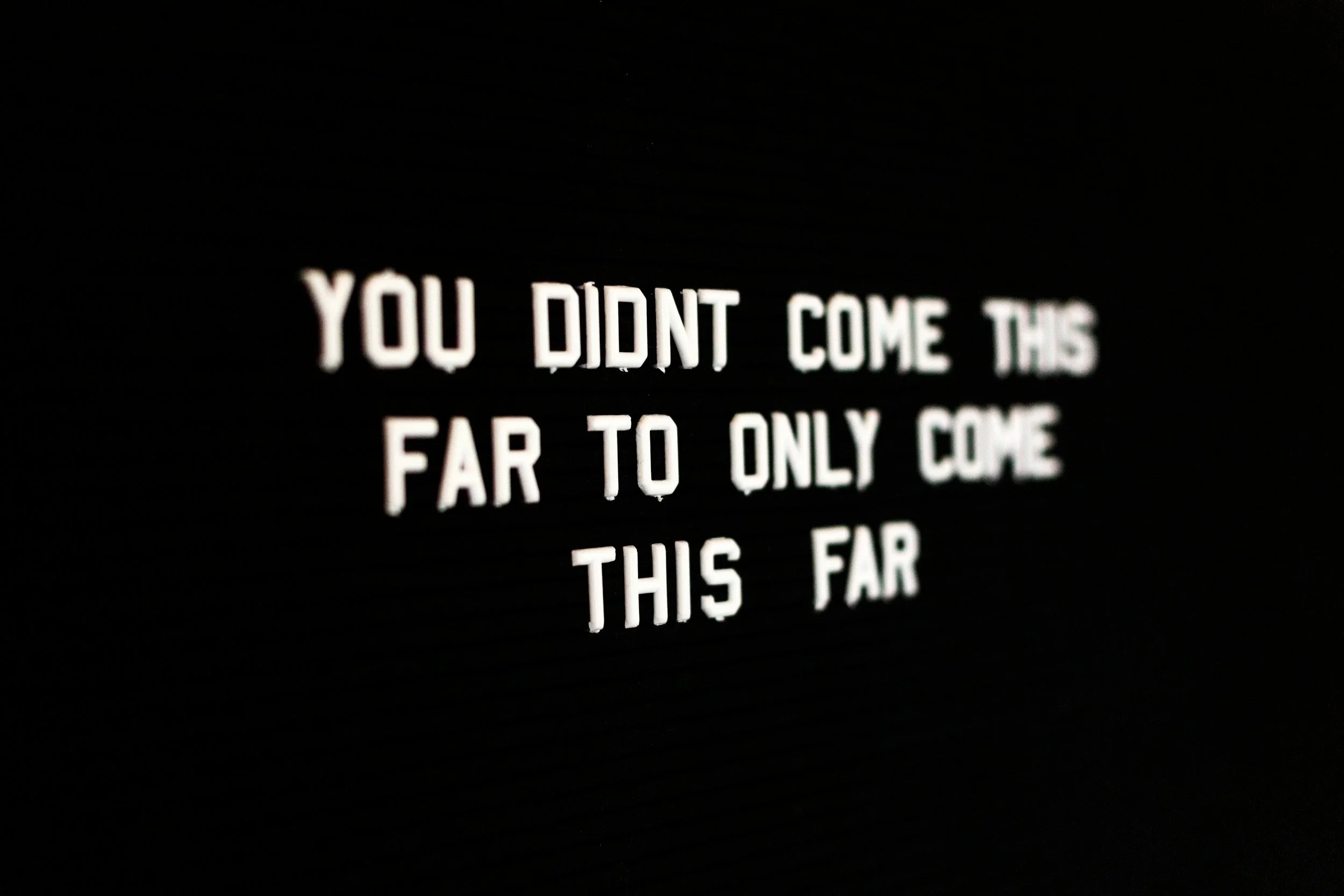 Close-up of a black background with white text that reads: 'You didn't come this far to only come this far'.