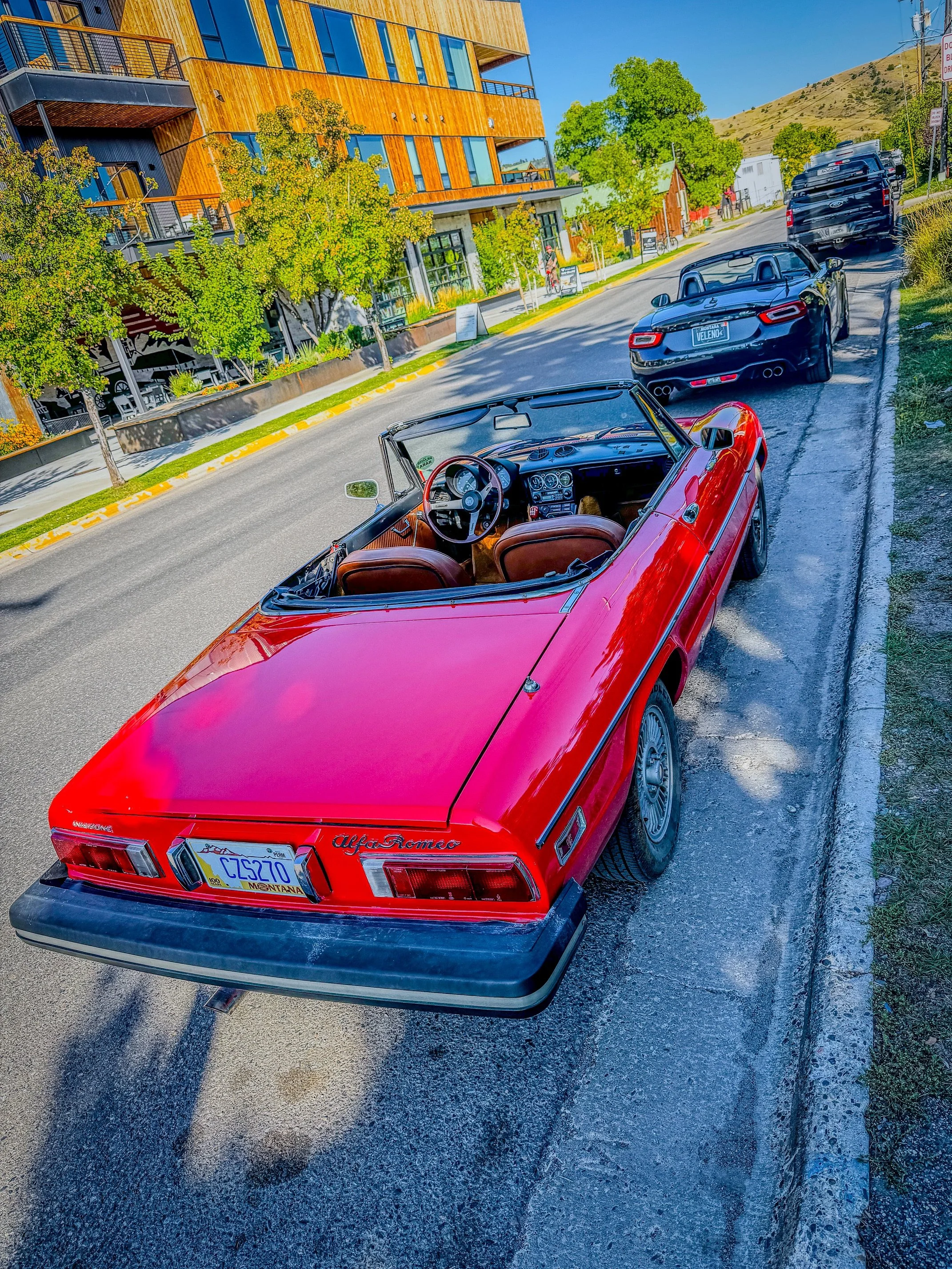 Red 1977 Alfa Romeo Spider parked on a downtown street