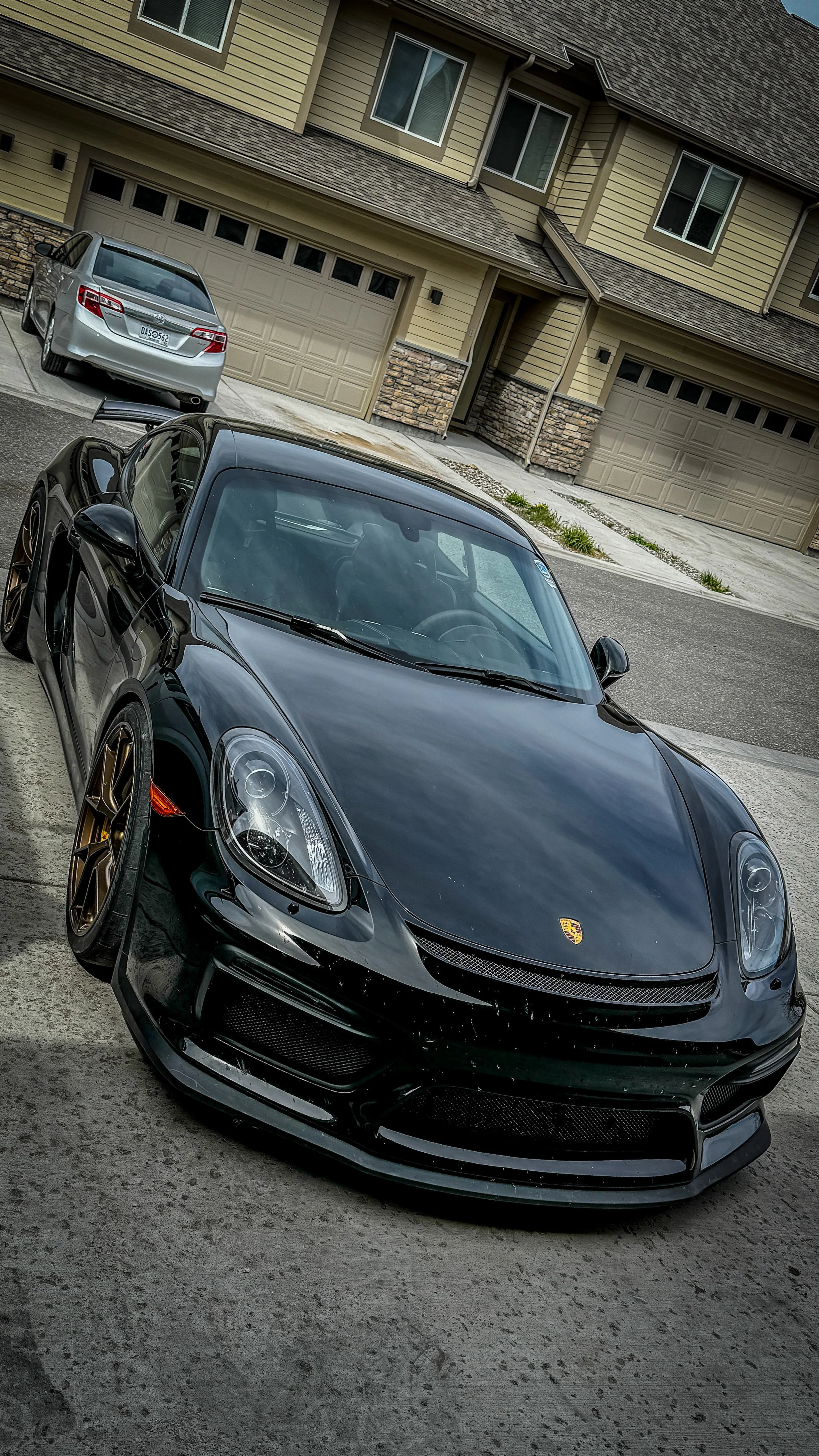 Black Porsche 718 Cayman GT4 in a driveway