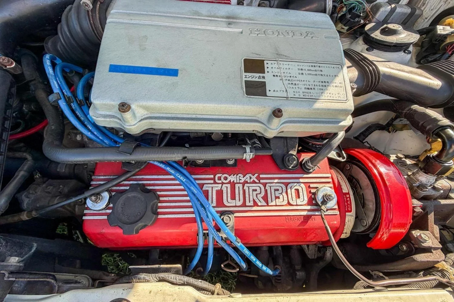 Red Combax Turbo valve cover with blue spark plug wires in the 1984 Honda City Turbo II engine bay
