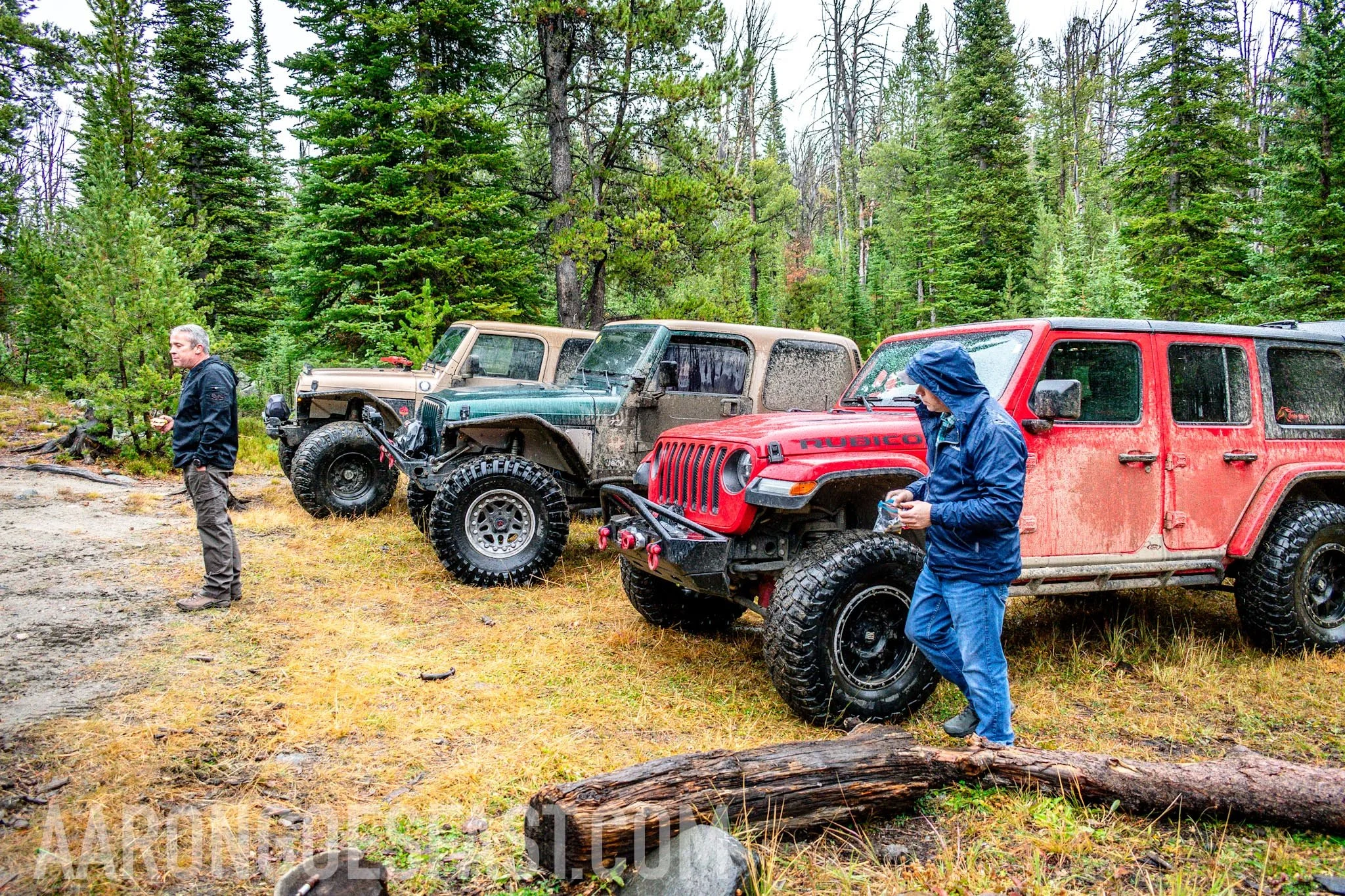 Red Jeep Wrangler with drivers nearby on the McElvy Lake trail in the Tobacco Roots