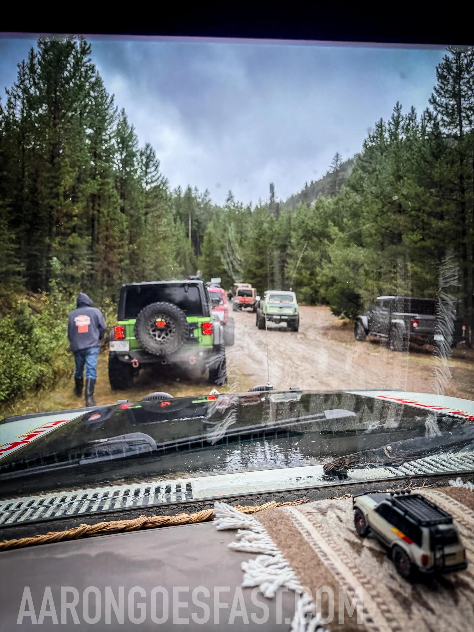 View through the windshield of rigs on a muddy forest trail on the McElvy Lake trail in the Tobacco Roots