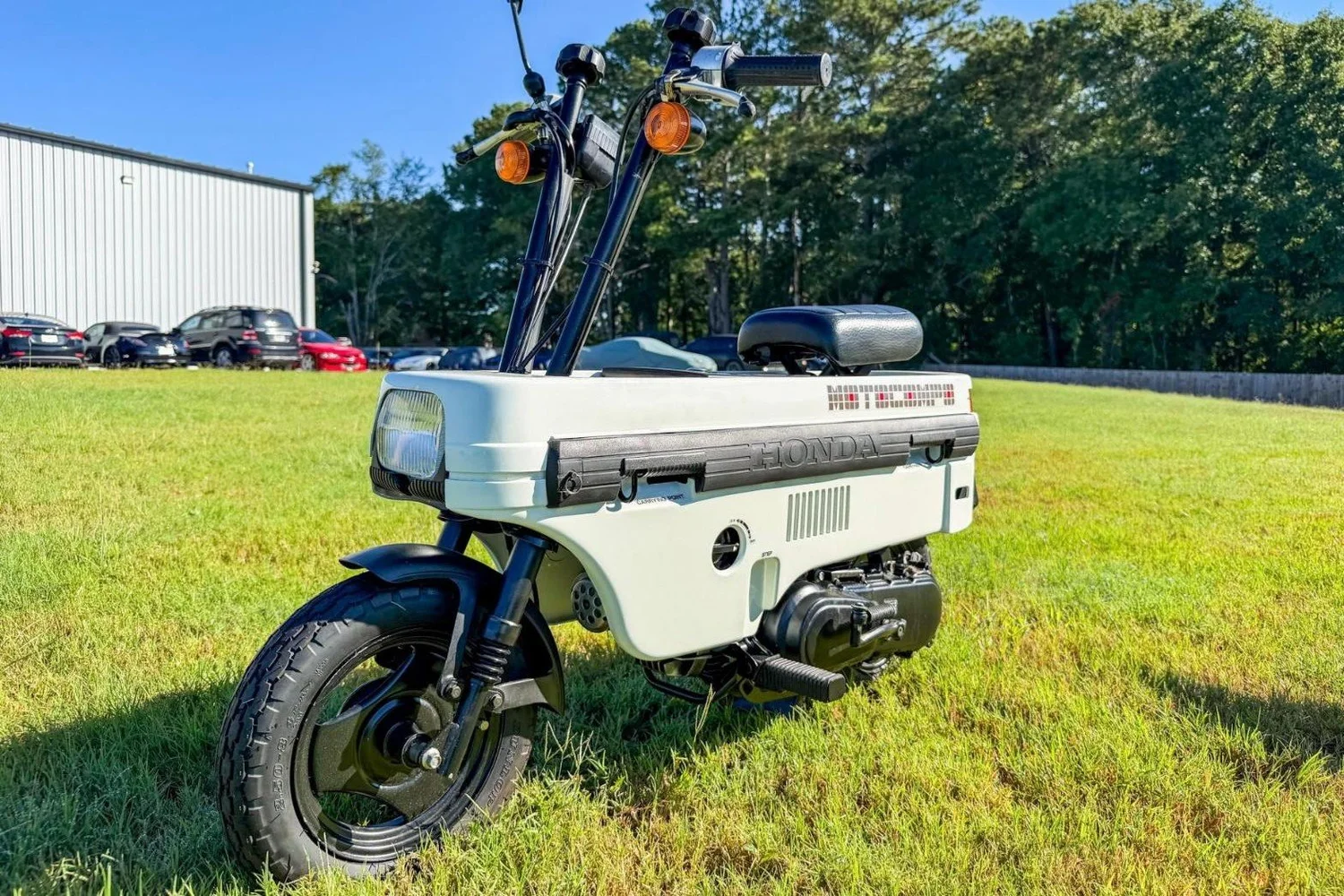 Honda Motocompo scooter unfolded with handlebars up and seat out, parked on grass