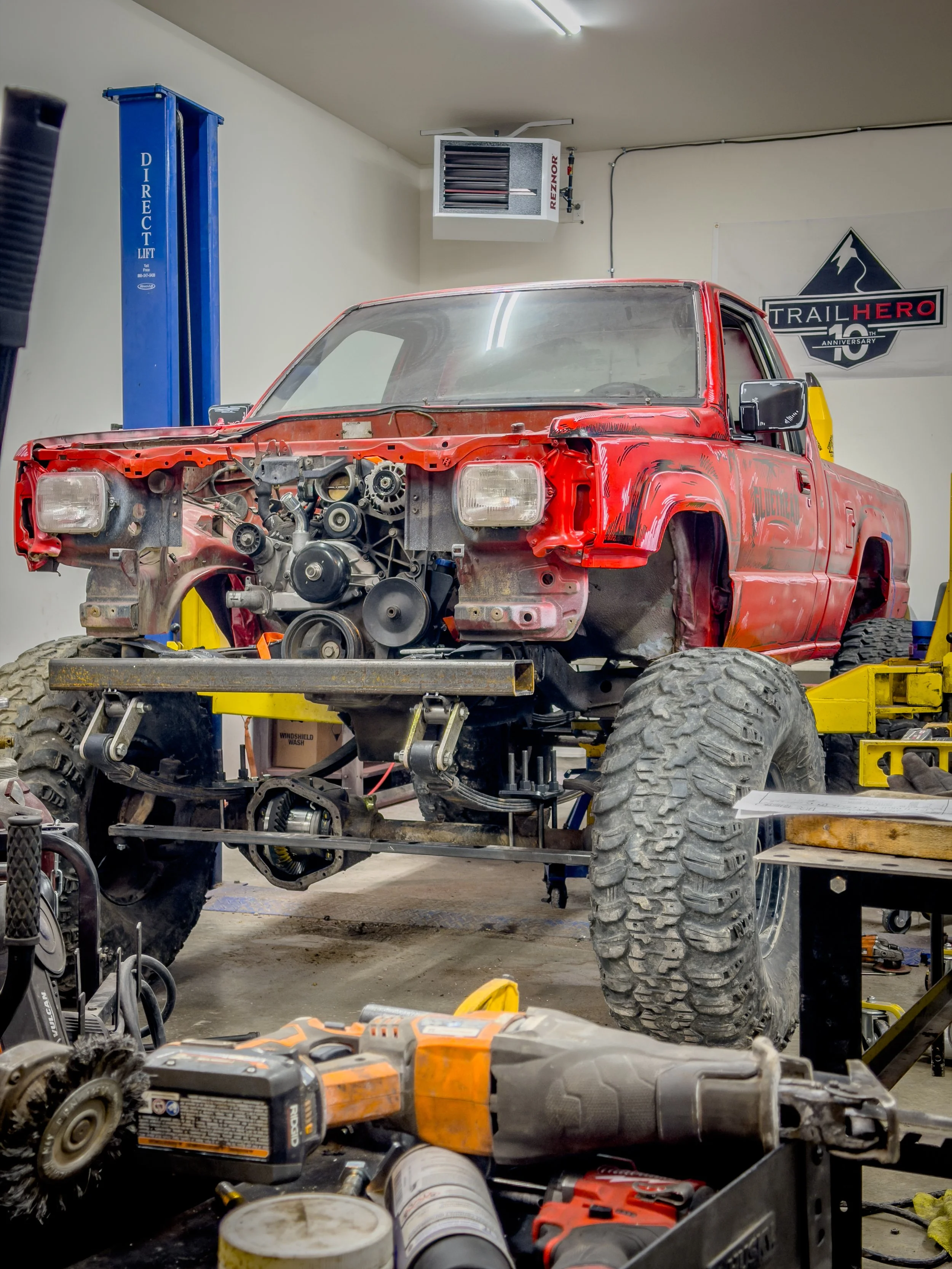 Red pickup chassis mid-build in a shop