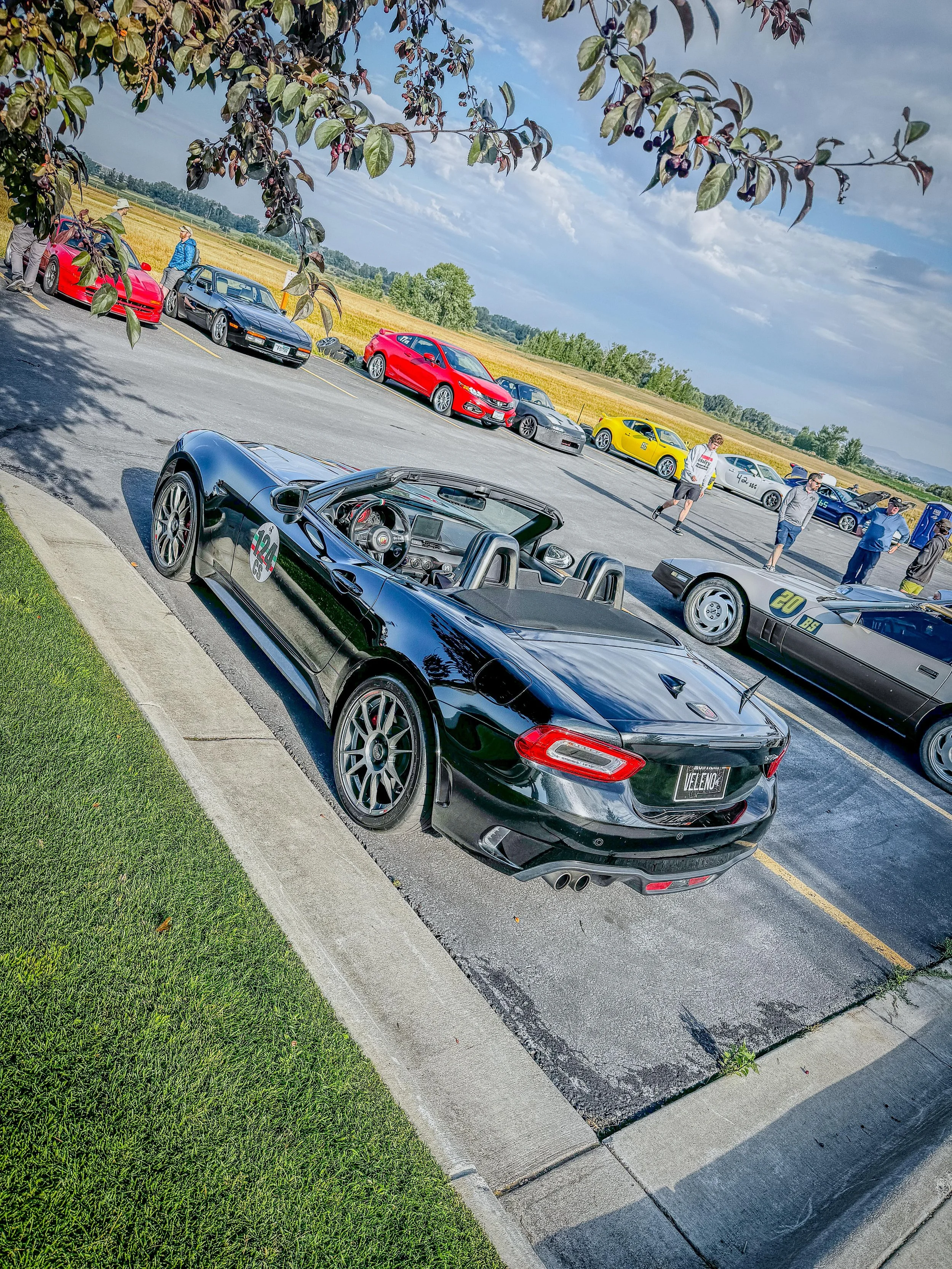 Black Fiat 124 Spider Abarth in a racetrack paddock