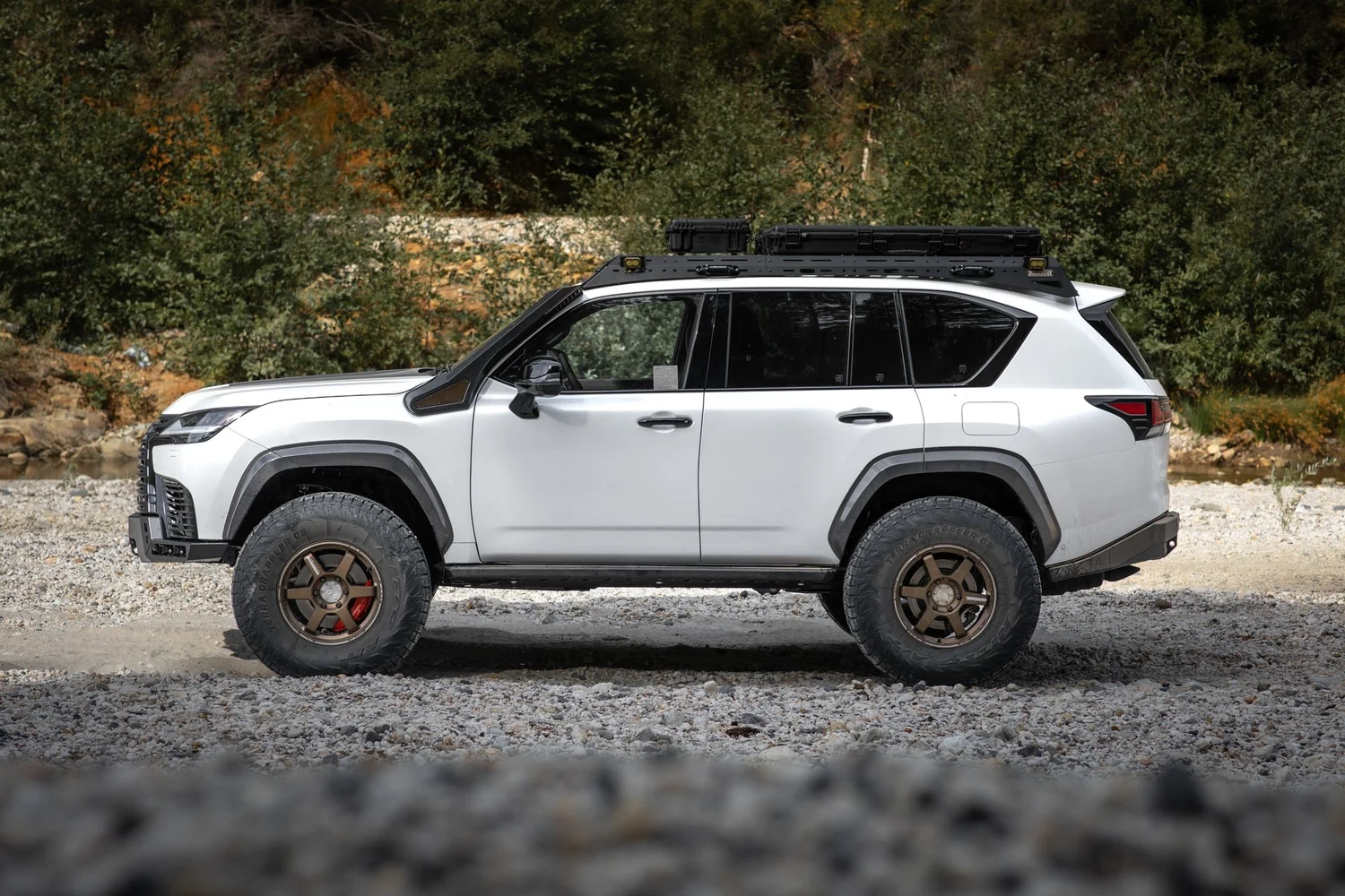 Side profile of the Dissent Off-Road Lexus LX 700h showing aluminum rock sliders and 37-inch tires