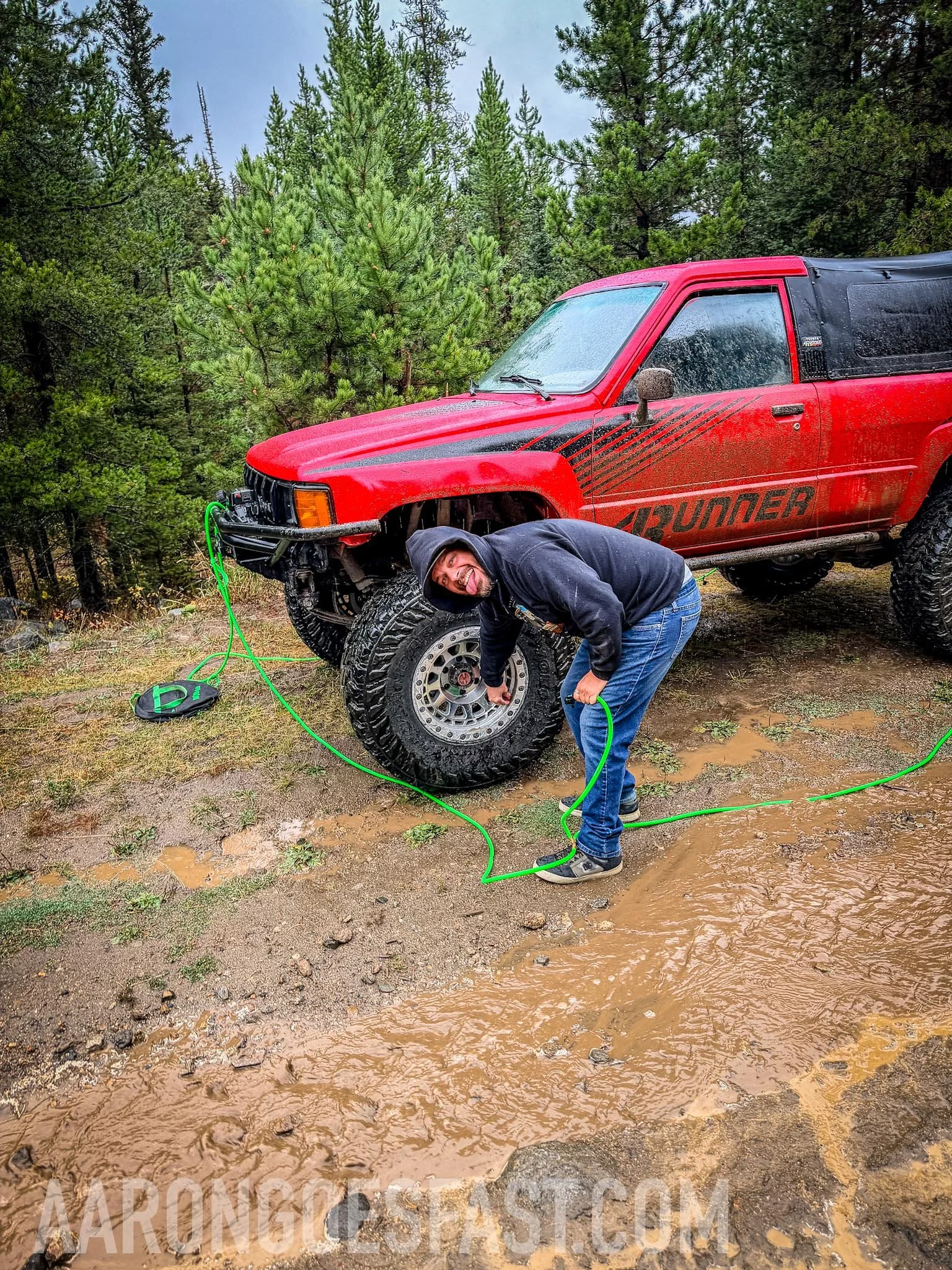 Driver checking under a red first-gen Toyota 4Runner on the McElvy Lake trail in the Tobacco Roots