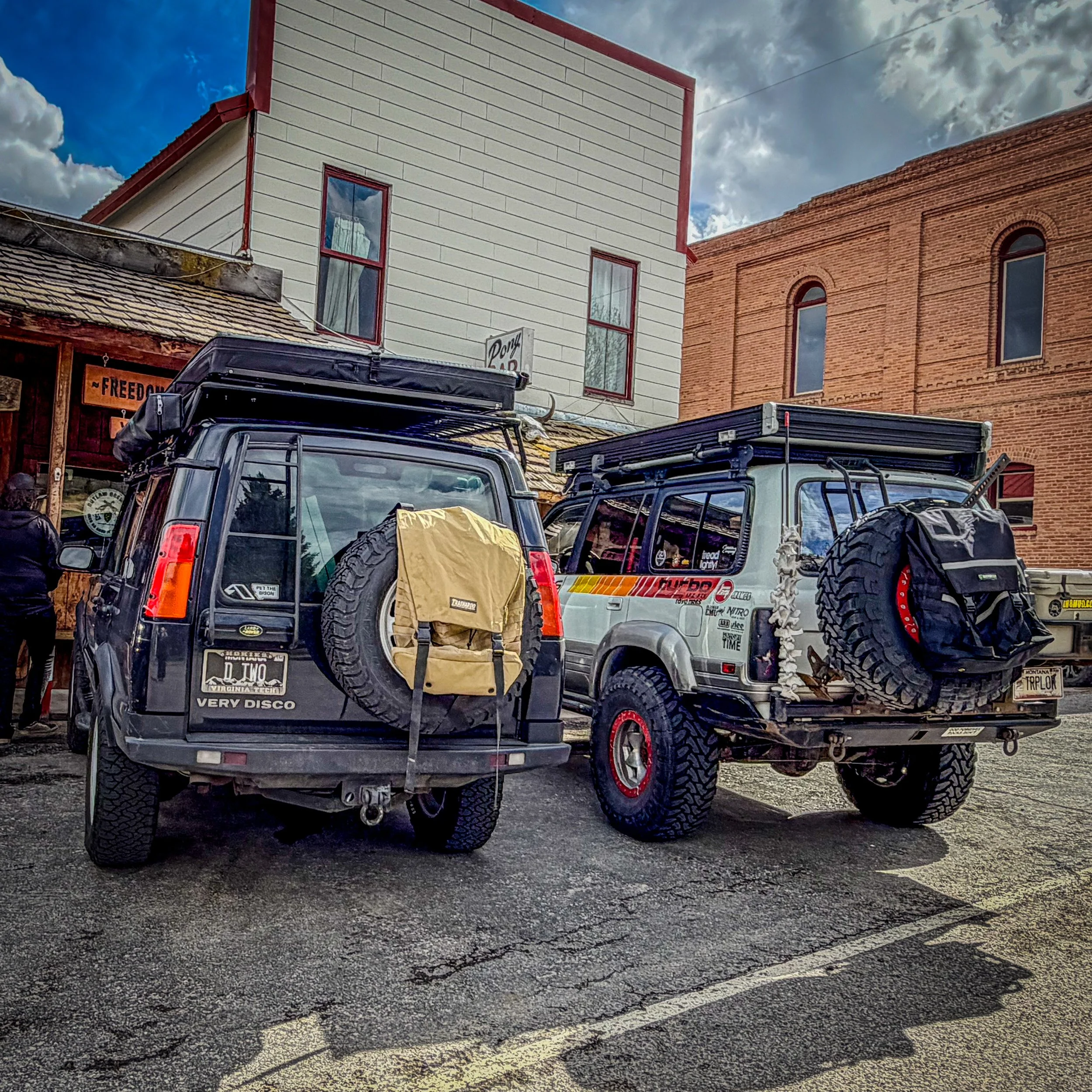 Two off-road rigs parked on a small-town street
