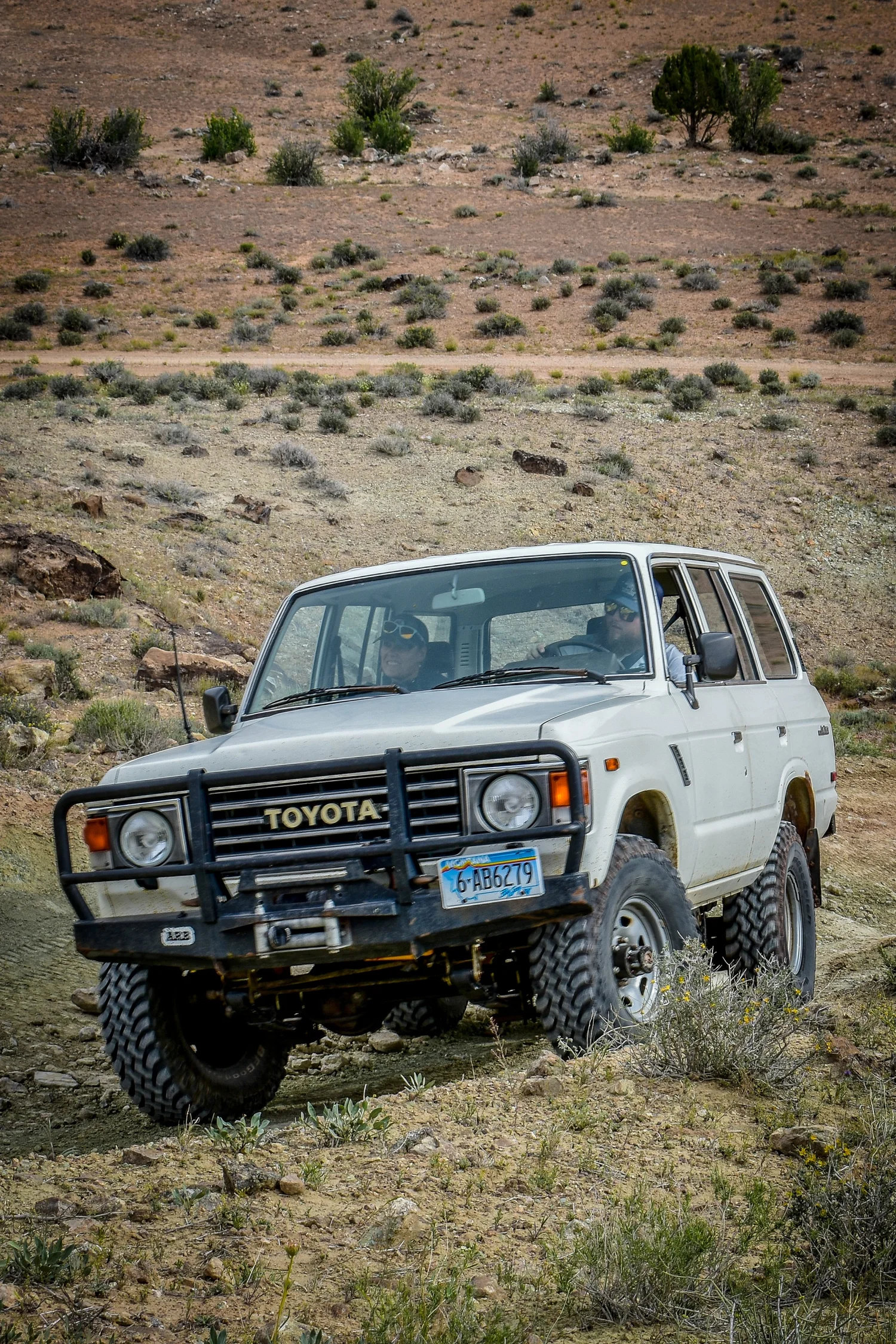 White Toyota Land Cruiser 60 Series climbing a desert trail