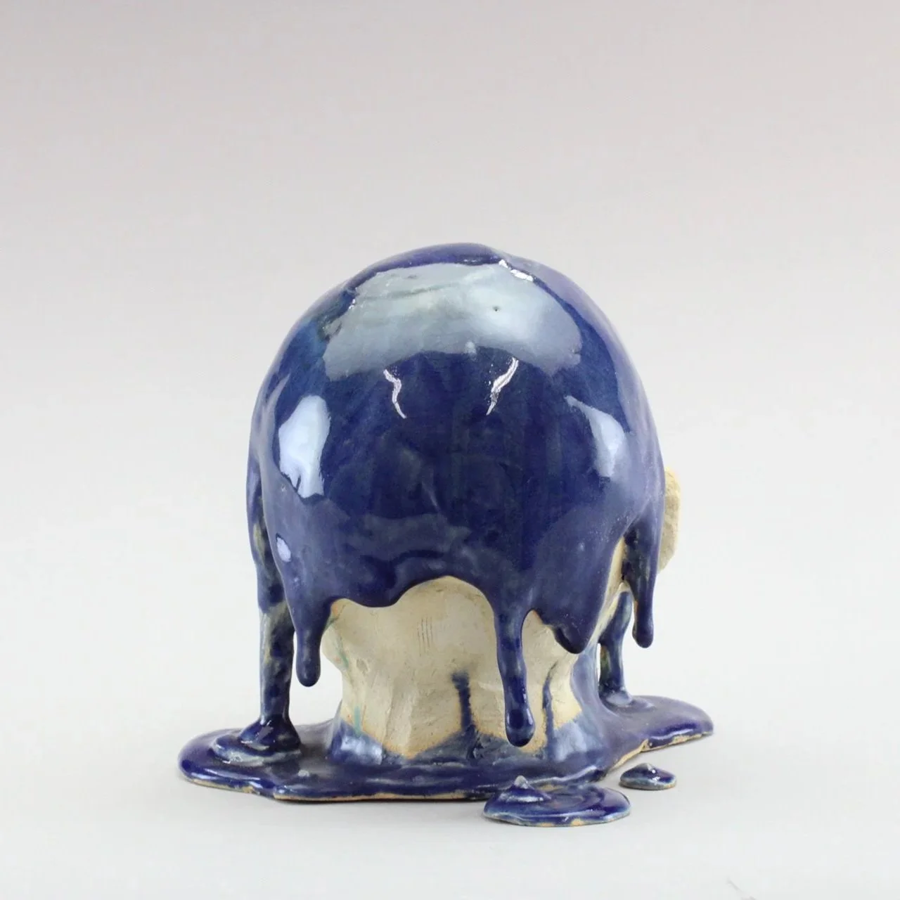 A ceramic sculpture of a head with dark blue glaze dripping down, by Anna Ford.