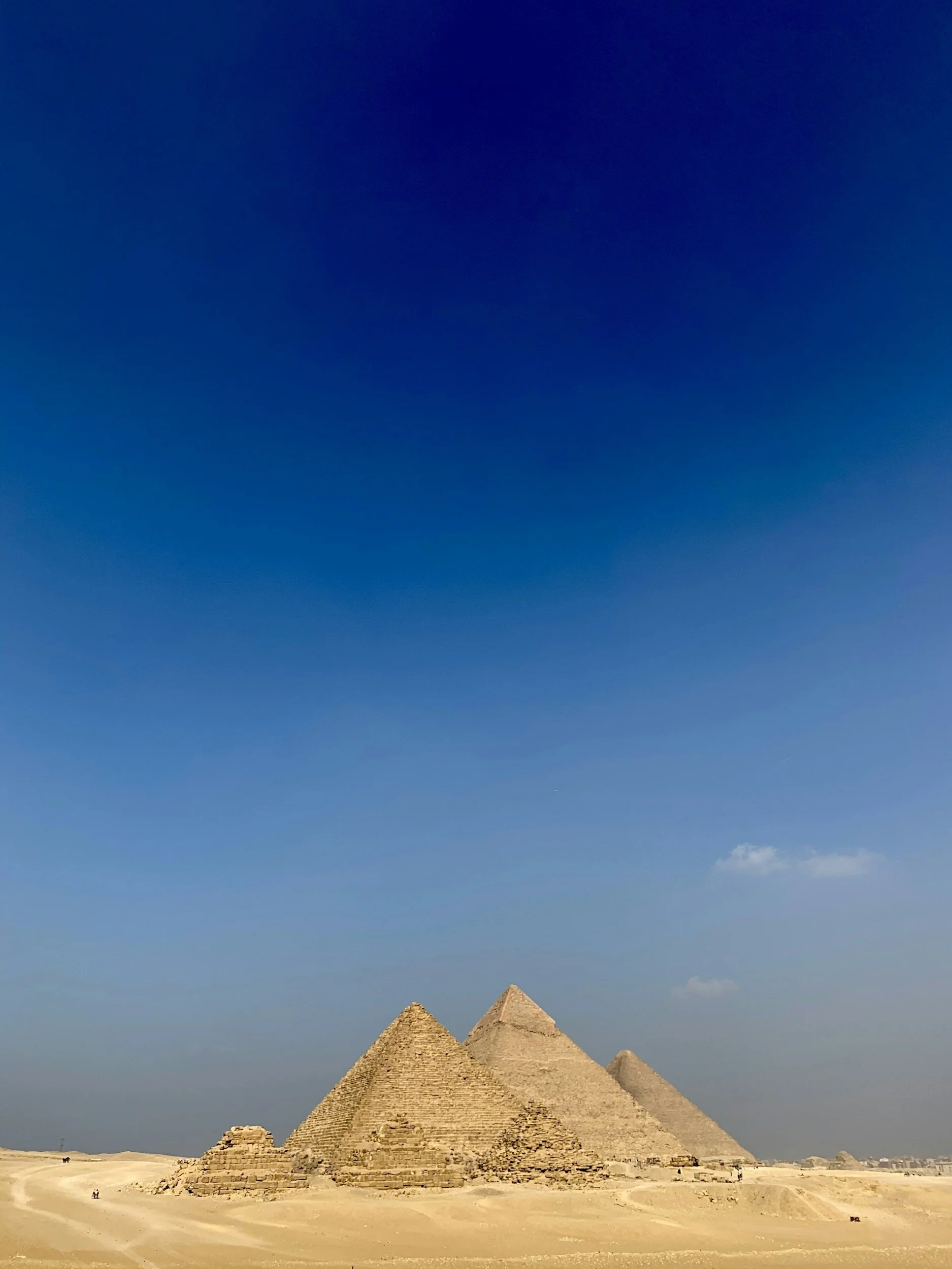 Three ancient Egyptian pyramids in a desert landscape under a clear blue sky.