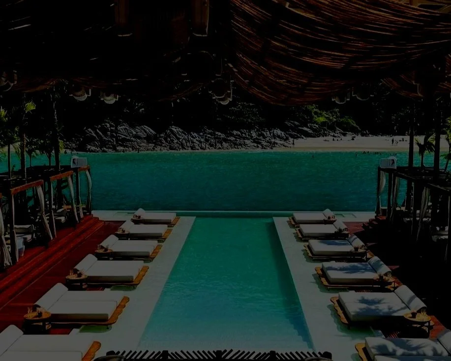 Overwater lounge chairs and a swimming pool overlooking the ocean at a tropical resort