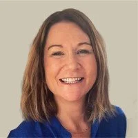 A woman with shoulder-length brown hair wearing a blue top, smiling at the camera.