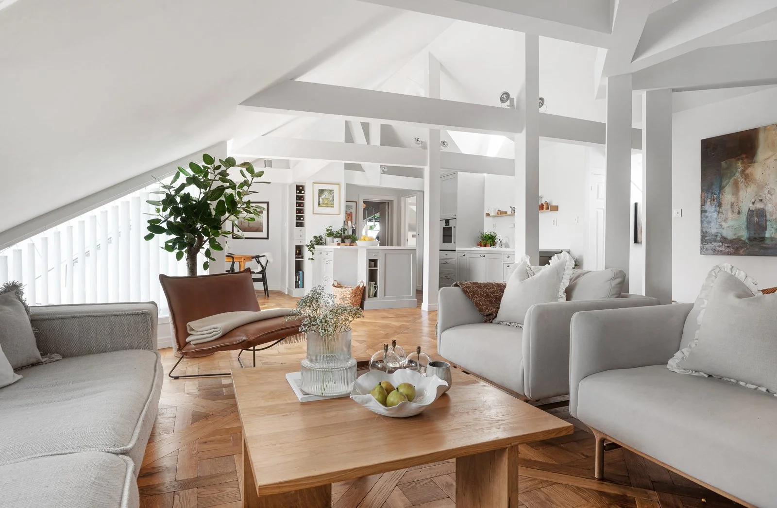 Stue med hvite sofaer, et treskap, grønt planter og et betongbord i tre.