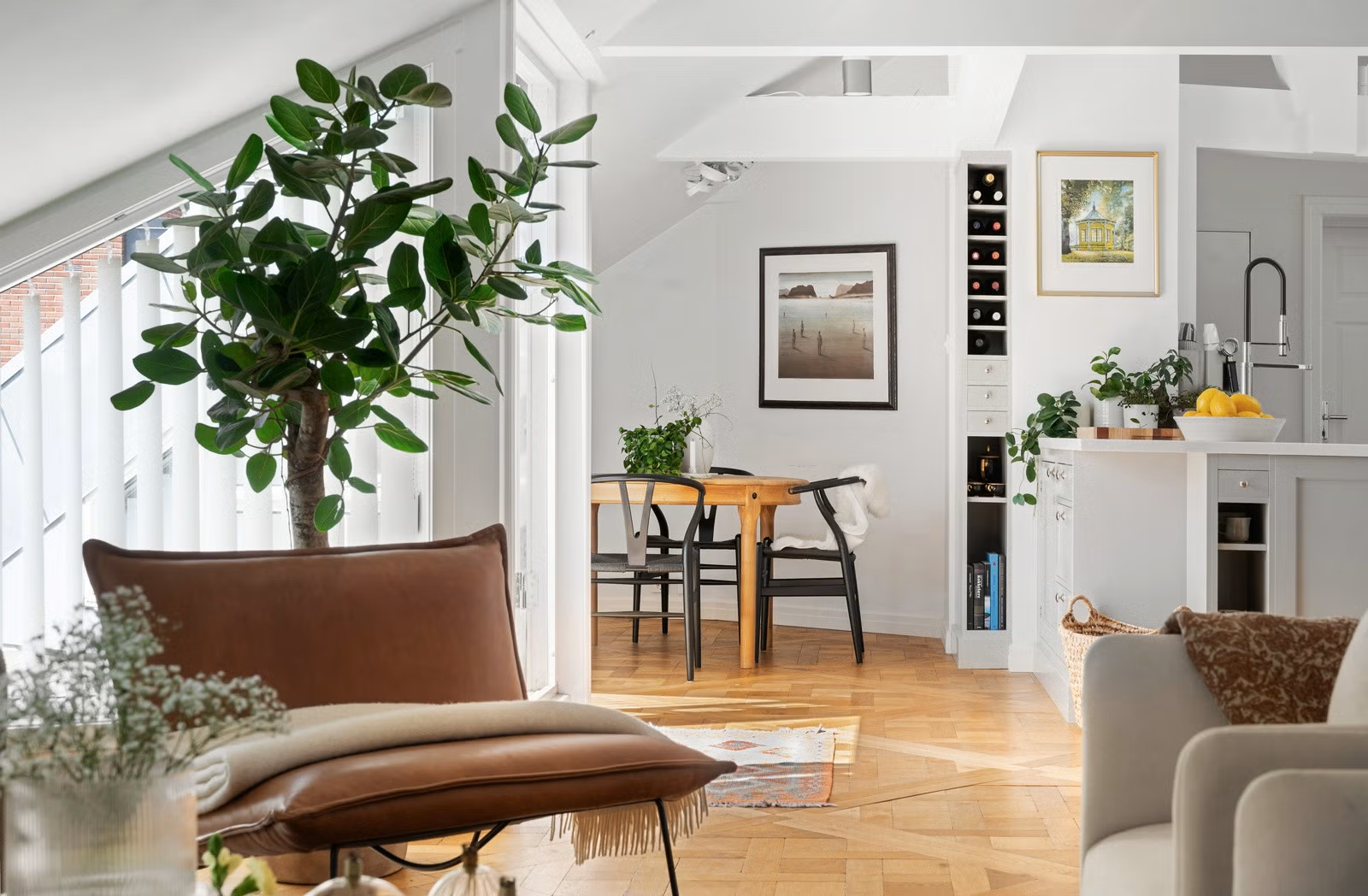 Stue med hvite sofaer, et treskap, grønt planter og et betongbord i tre.