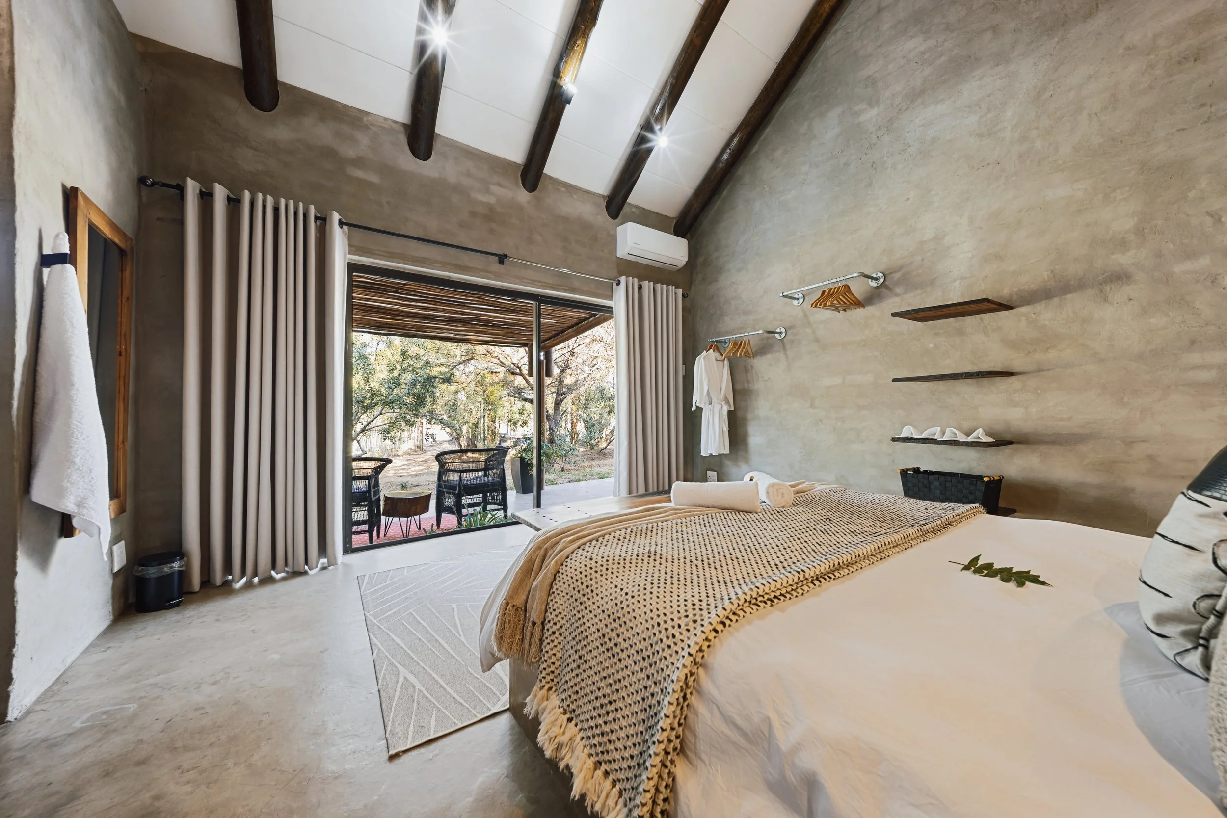 Bedroom with textured beige walls and sliding doors opening to a private patio — Moditlo, Greater Kruger.