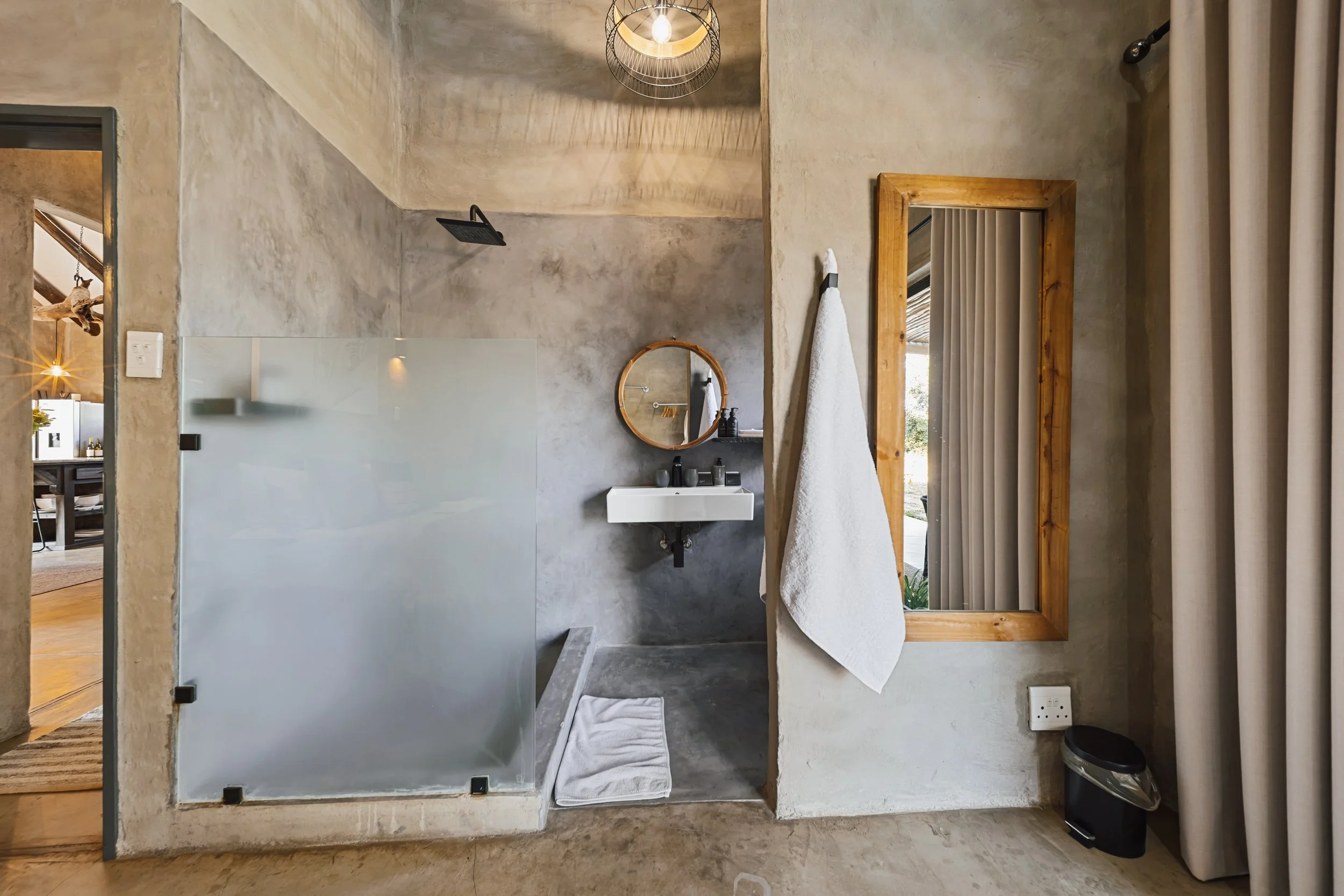 Modern en-suite bathroom with concrete walls and a glass-enclosed shower. 