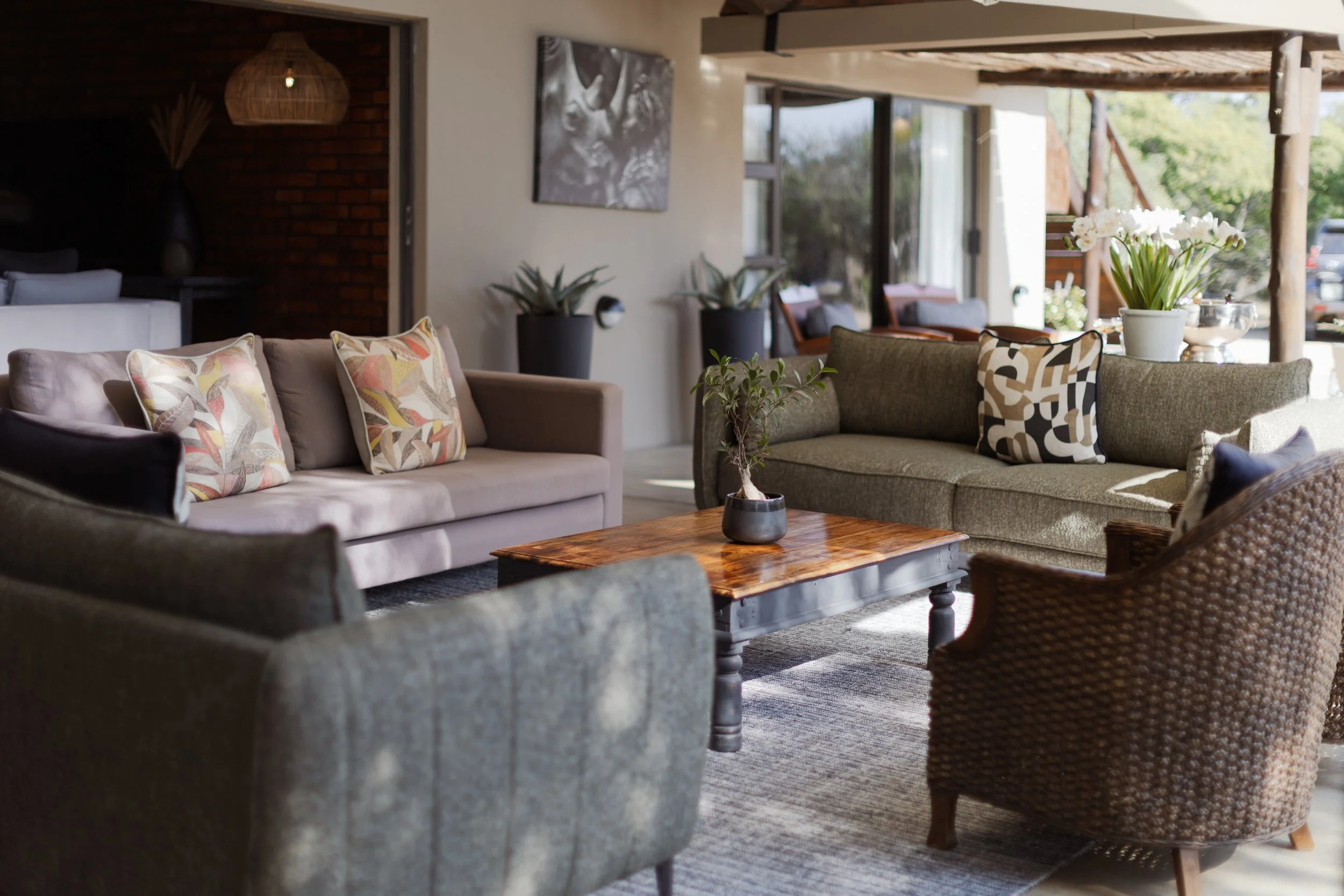 Living room with covered sofas, wooden coffee table and large windows onto the bush — Moditlo, Greater Kruger.
