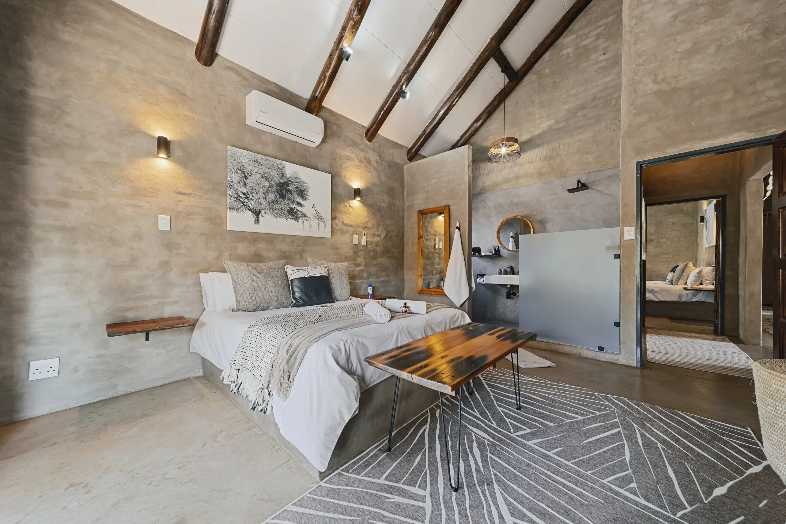 Bedroom with stone wall, wooden ceiling beams and giraffe painting. 