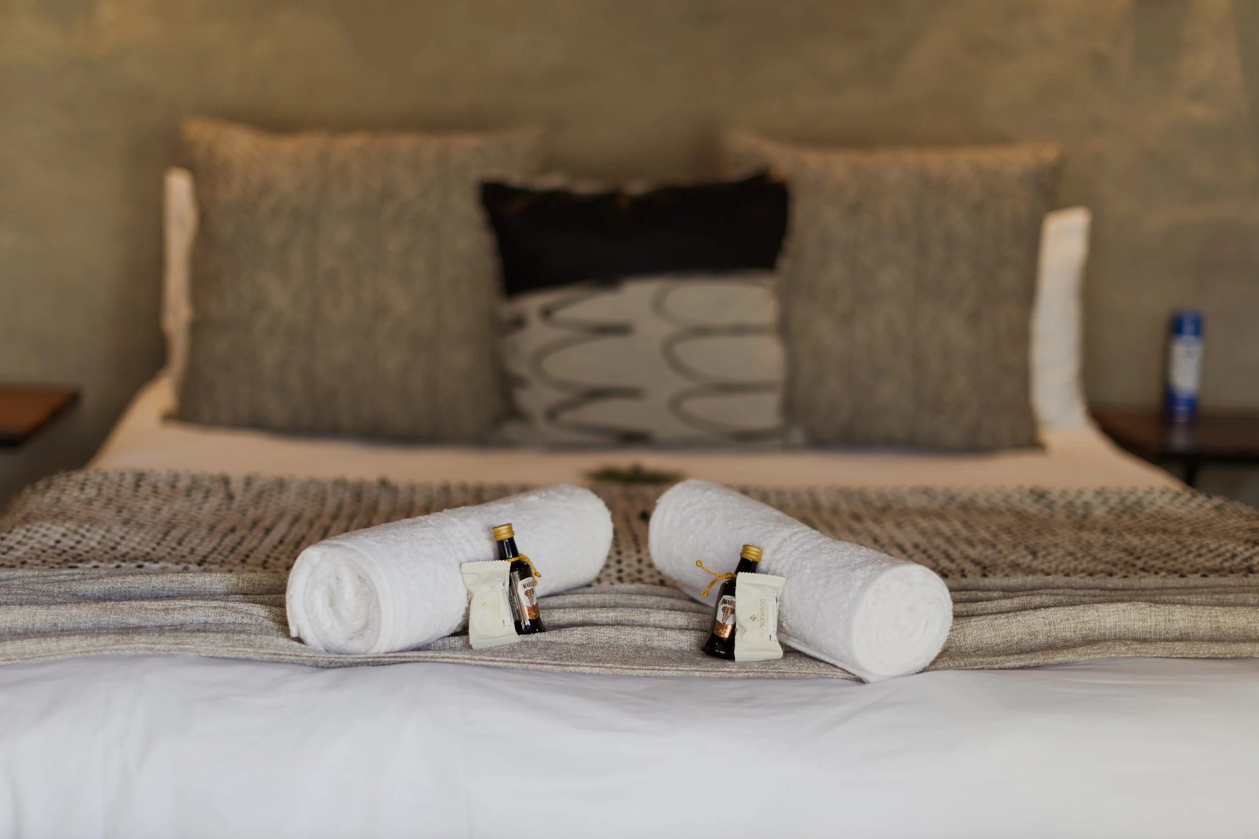 Rolled towels and toiletries laid out on a made bed — guest suite in Hoedspruit, Limpopo. 