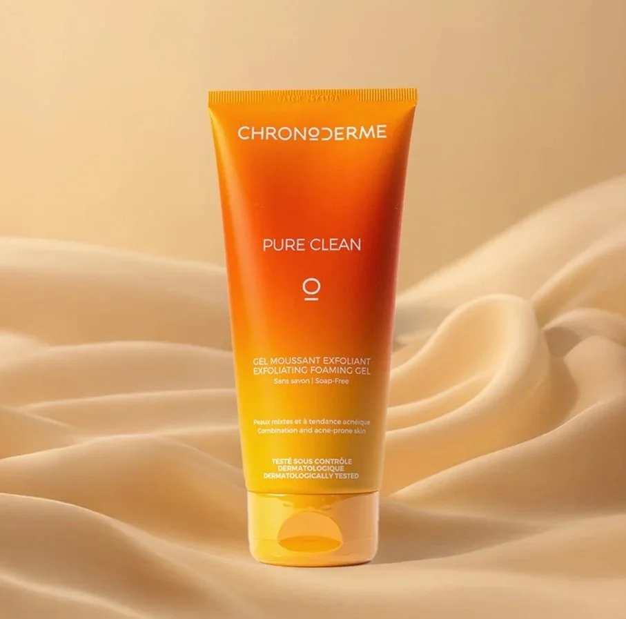 A tube of Chronoderme Pure Clean IO exfoliating foaming gel on a soft, beige fabric background.