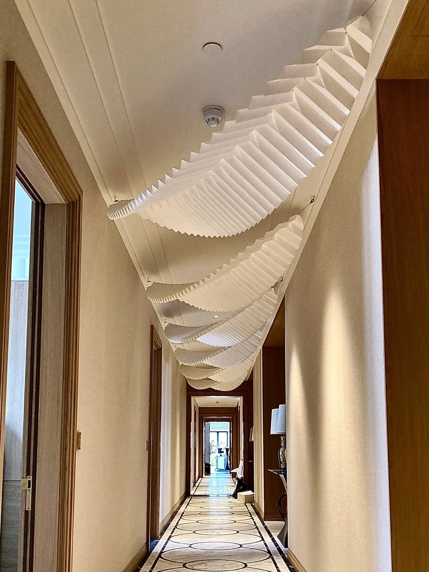 Decorative wave-like paper streamers hanging from the ceiling in a hotel hallway.