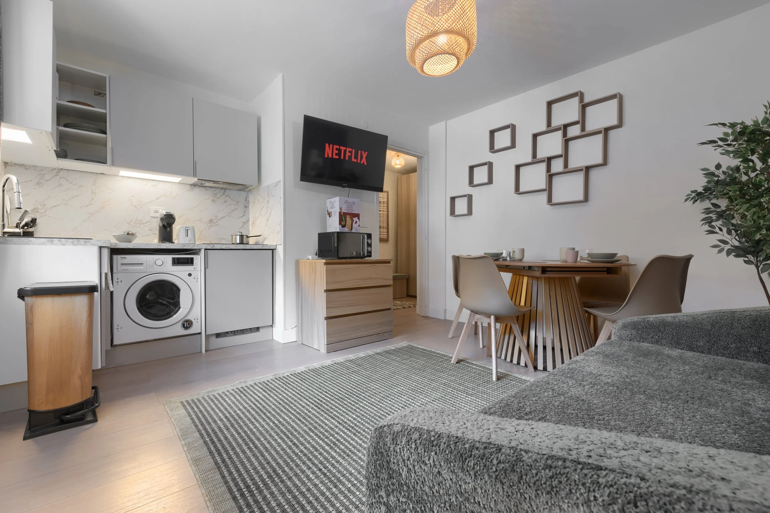Living area with kitchen, dining table, gray couch, wall-mounted TV, and decorative wall art, a luxurious retreat, an exclusive retreat, a refined mountain retreat, a premium alpine retreat.
