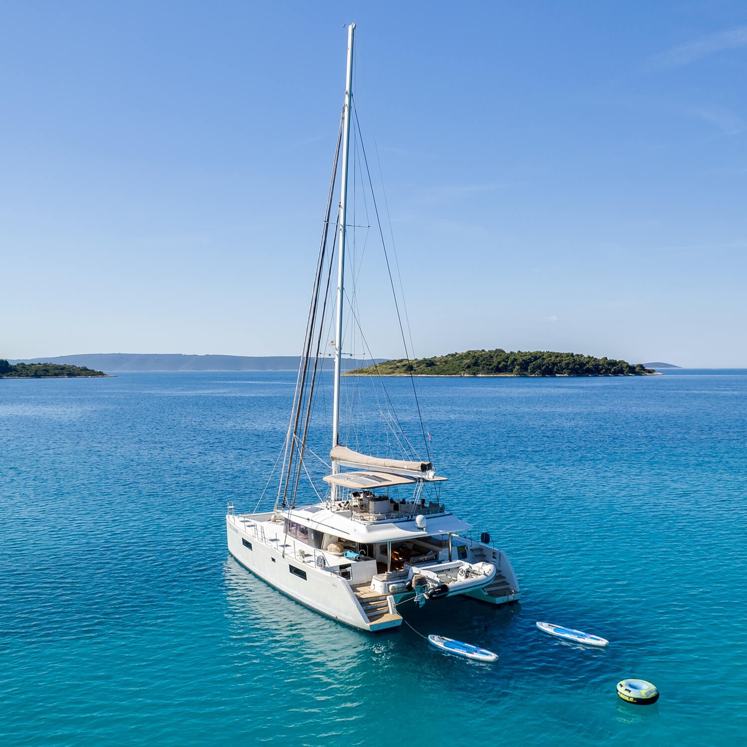 Catamaran Cool Change on calm blue water with an island in the background under a clear sky.