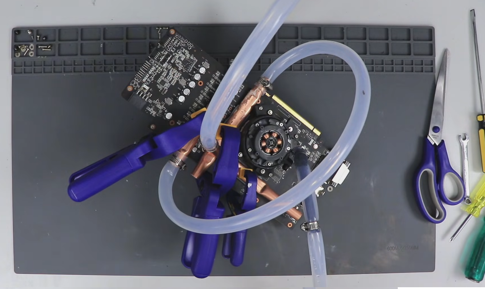 Workstation with a graphics card, coolant tubes, and tools for computer cooling or repair.